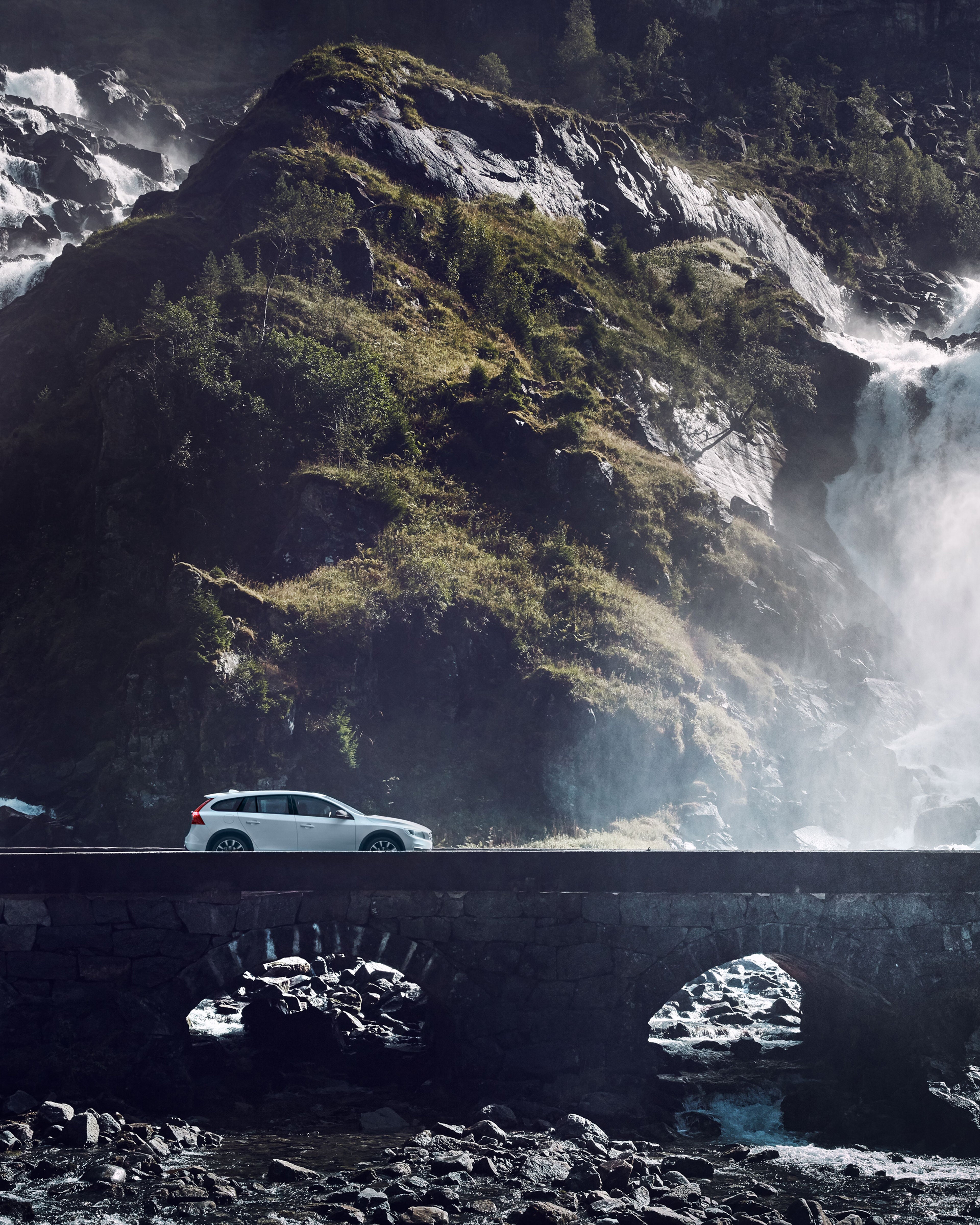 Volvo V60 påen gammal stenbro med ett vattenfall i bakgrunden.
