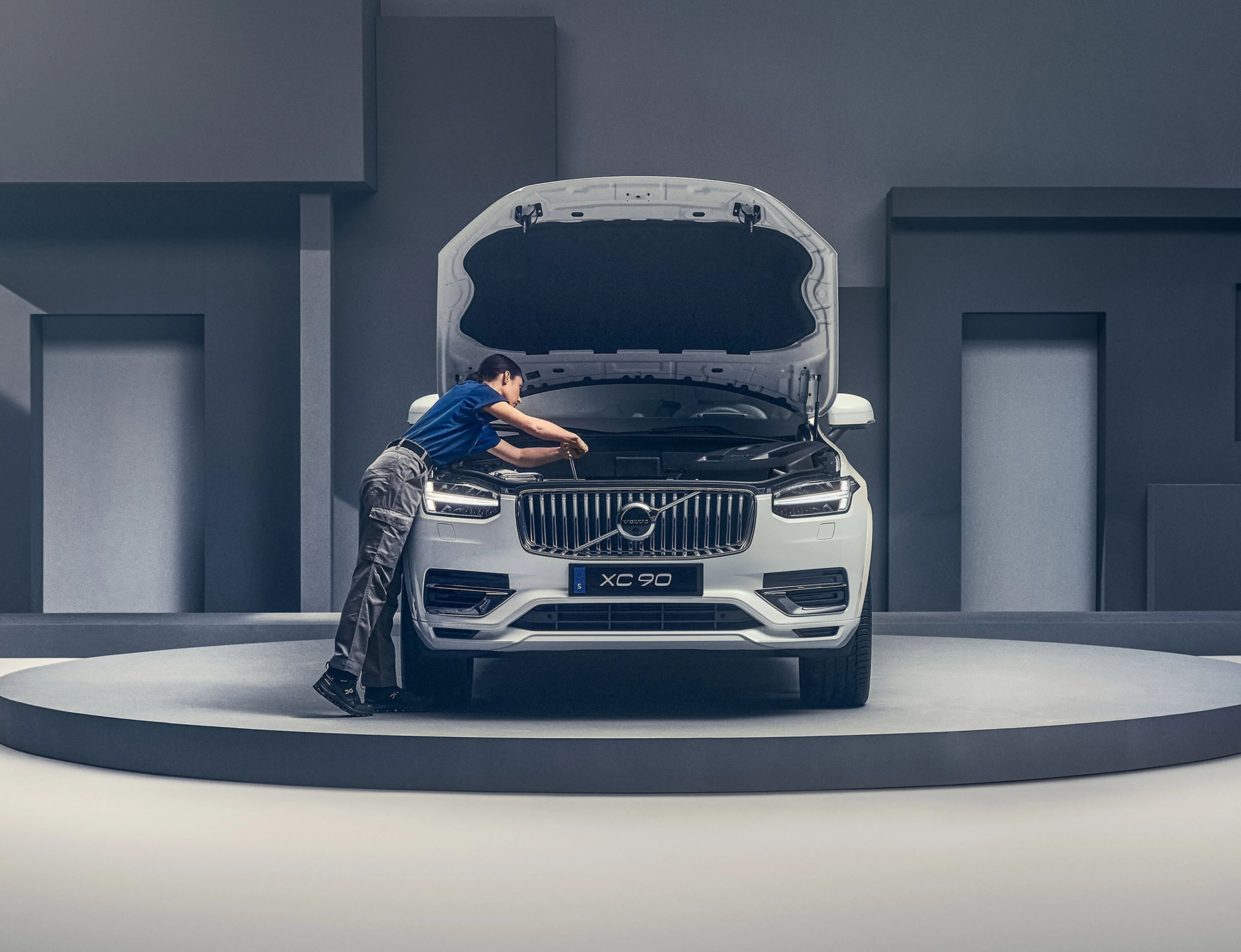 Une mécanicienne travaille sur le moteur d'un Volvo XC90 blanc.