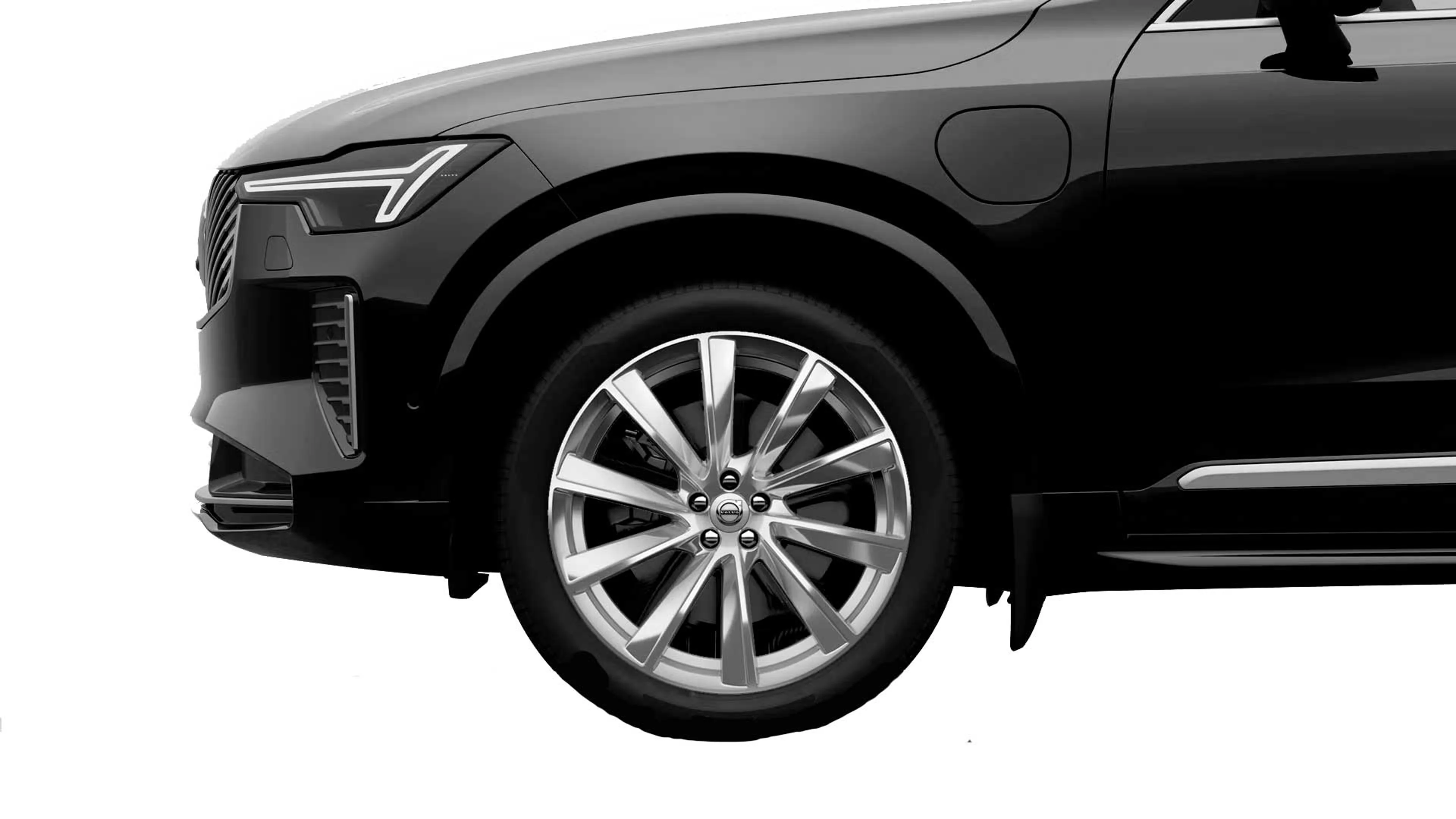Close-up af en elegant sort Volvo SUV's forside, der fremhæver moderne forlygter og en skinnende sølvfarvet alufælg, som udstråler luksus og sofistikering.