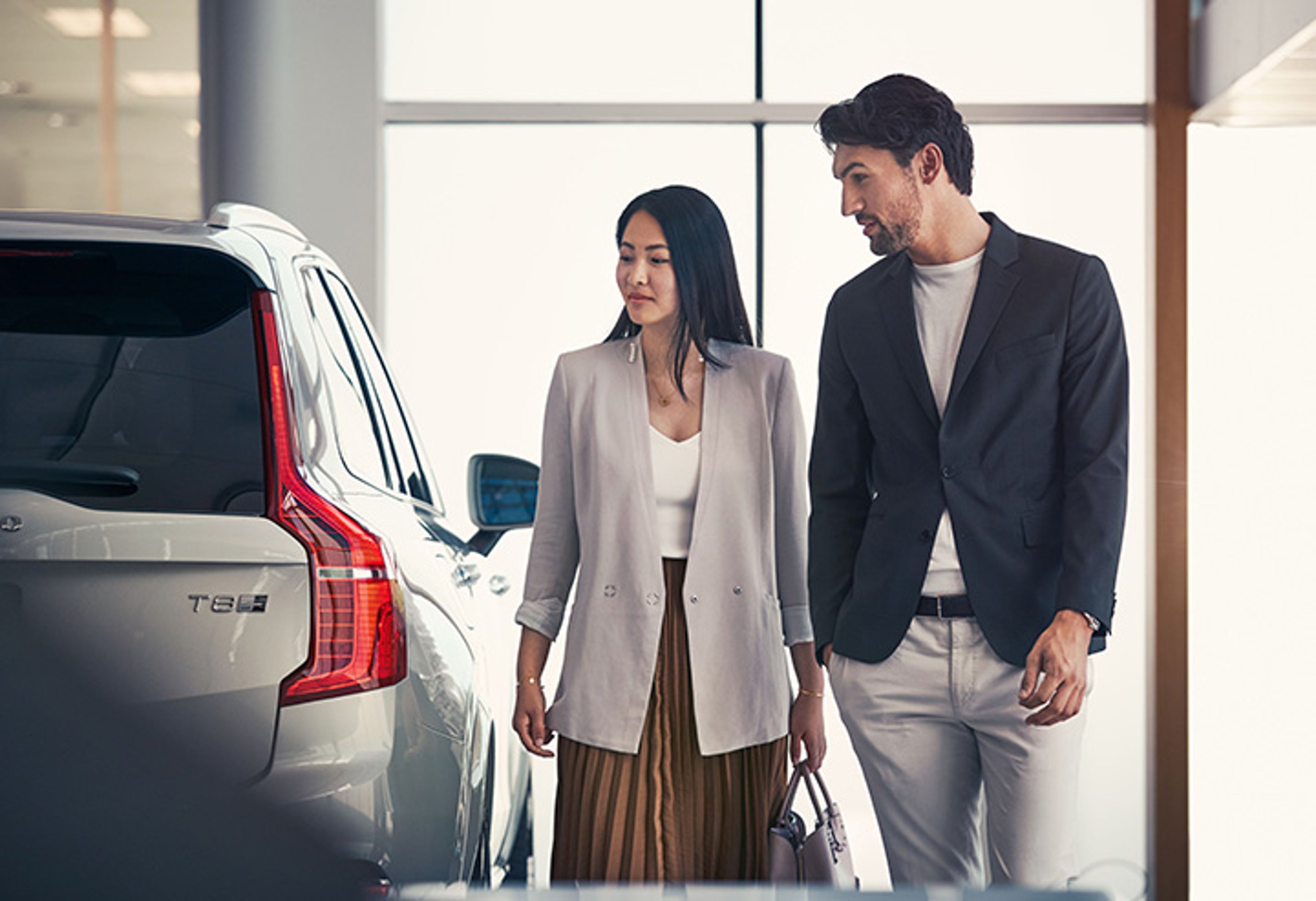 Ein Pärchen schaut auf einen silbernen Volvo XC90 SUV.