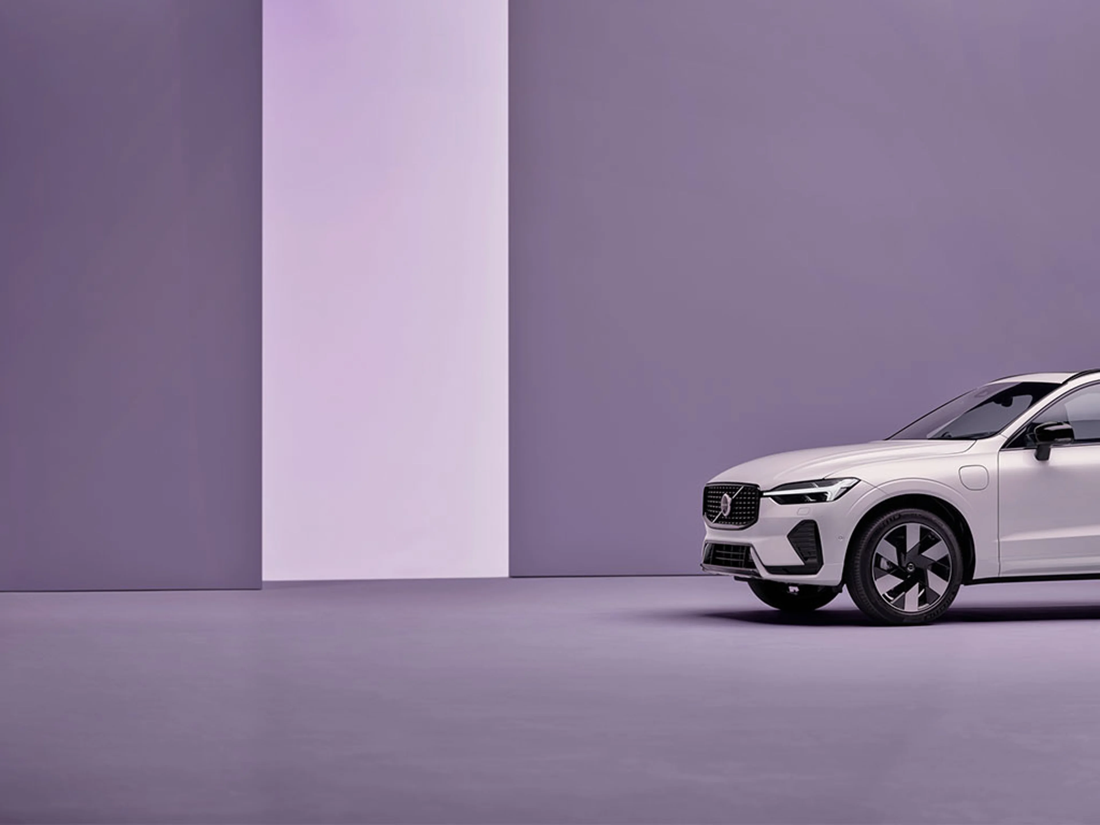 Vue partielle d’un SUV Volvo blanc dans une pièce minimaliste violette.
