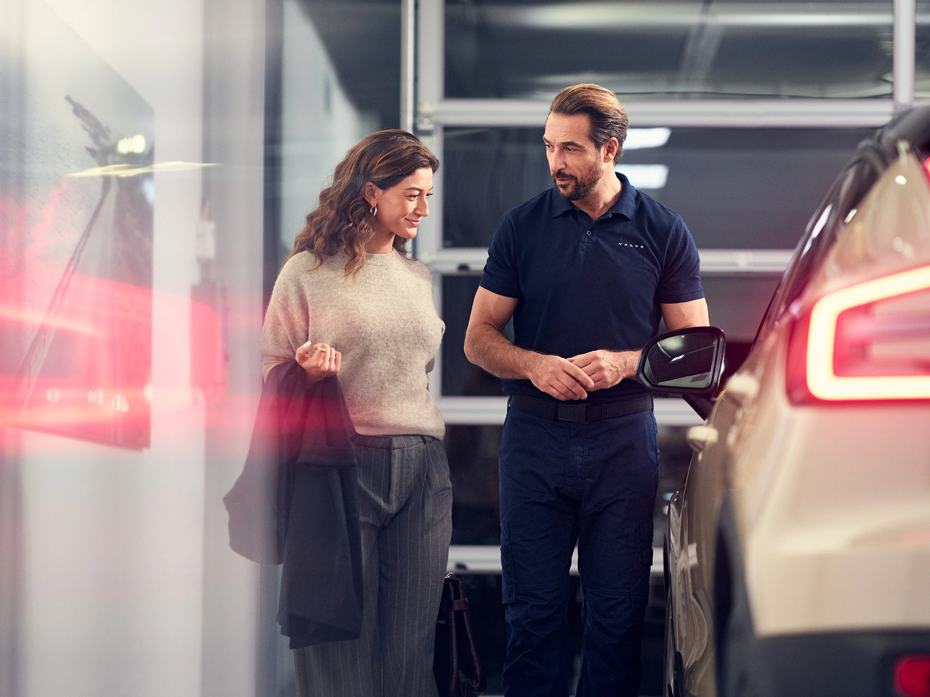 Funcinário da Volvo vestido de azul a dar infromações a uma mulher vestida de tons claros