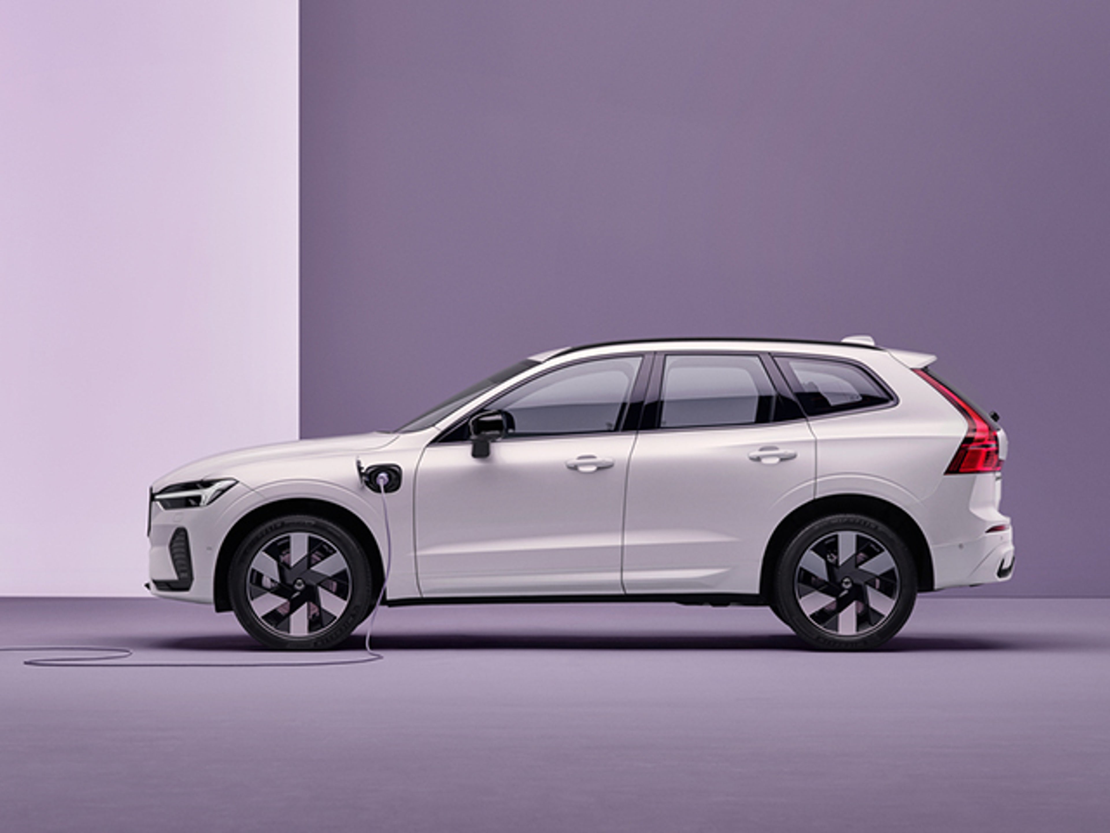 Vit Volvo XC60 Recharge från sidan i lila studiomiljö
