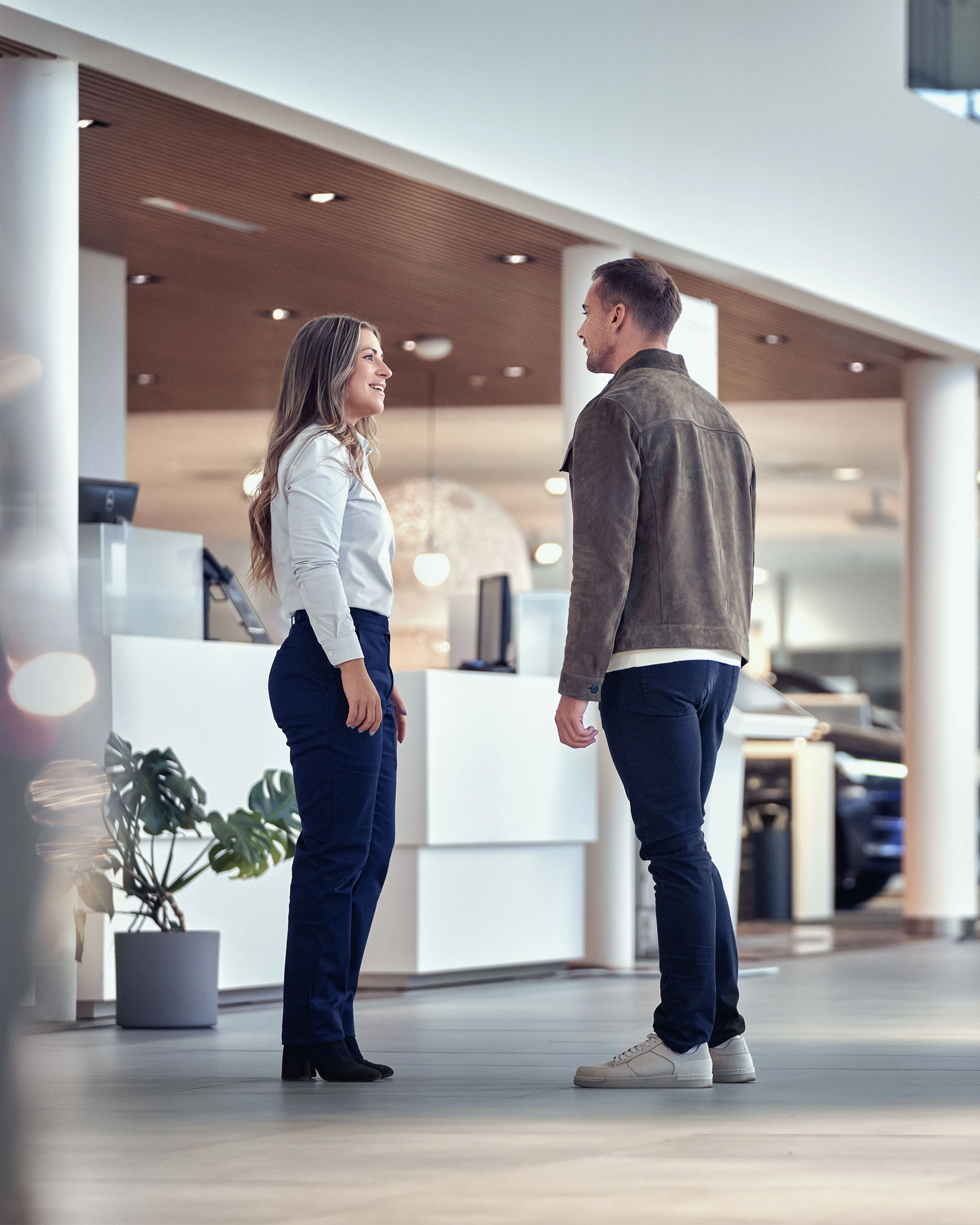 Un client discute avec un conseiller dans une concession Volvo moderne avec des voitures en arrière plan