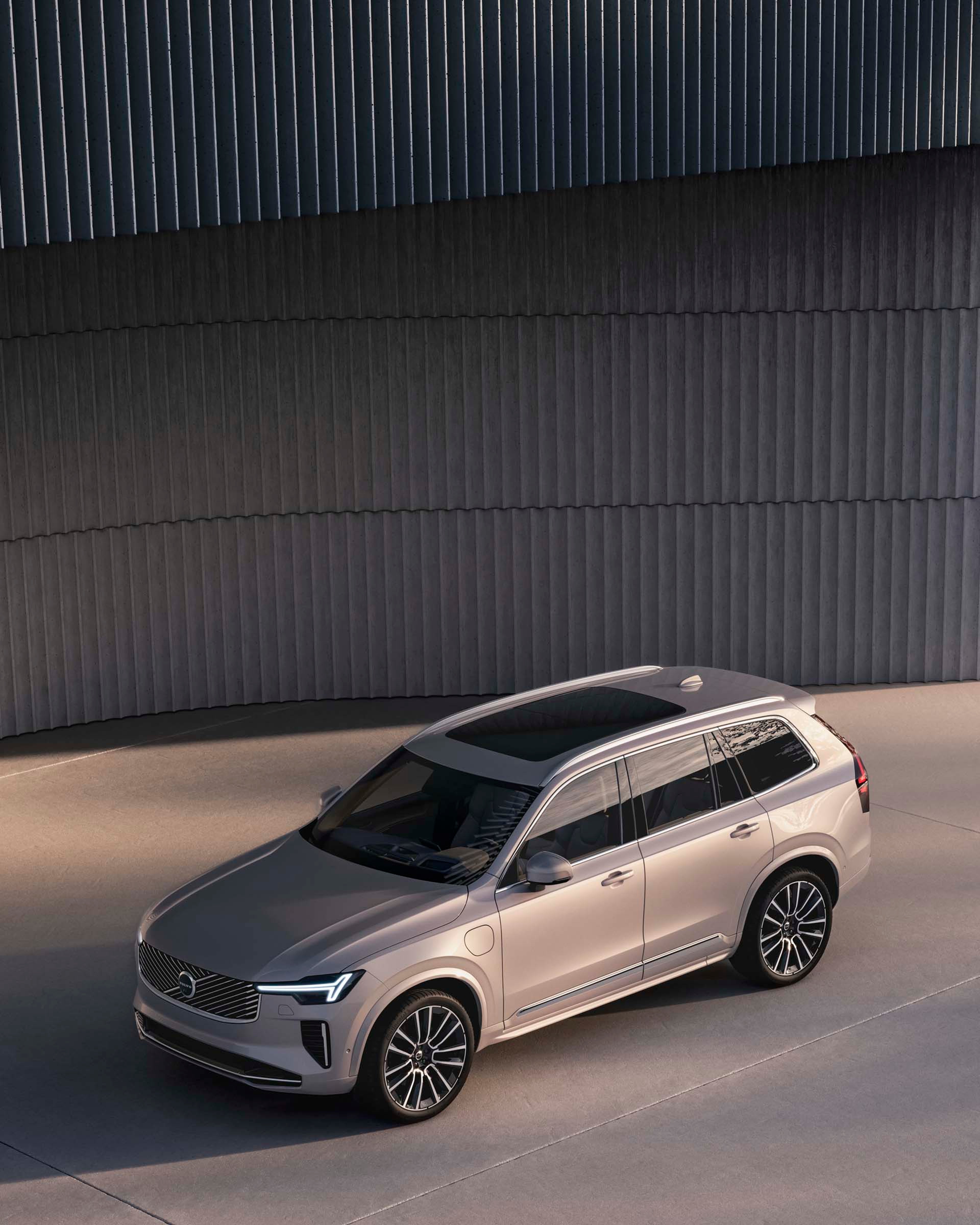 Volvo XC90 color sand dust vista aérea destacando su techo panorámico, sus luces LED y sus llantas aerodinámicas