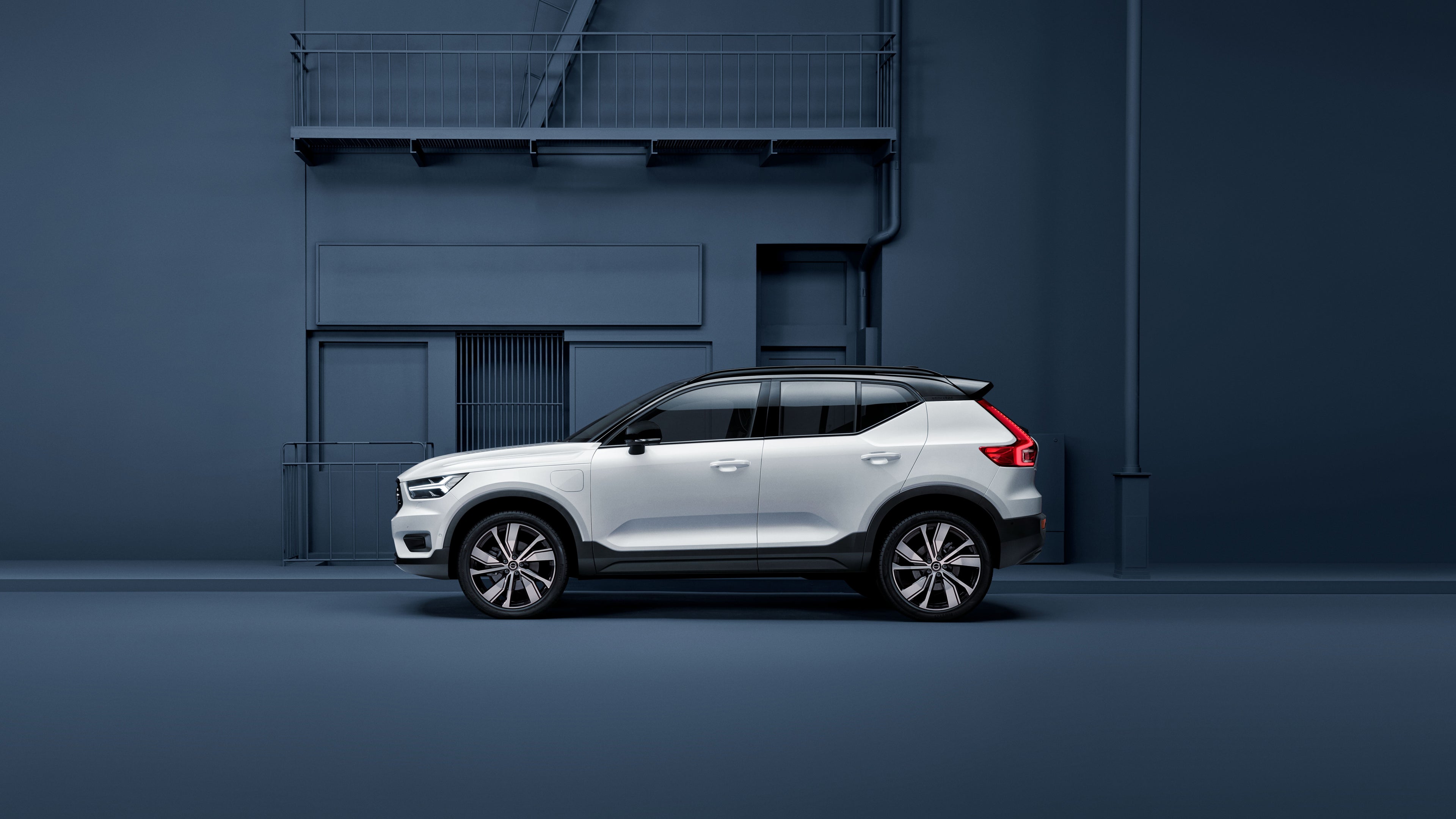 Side profile of a white Volvo EX40 with a blue background.