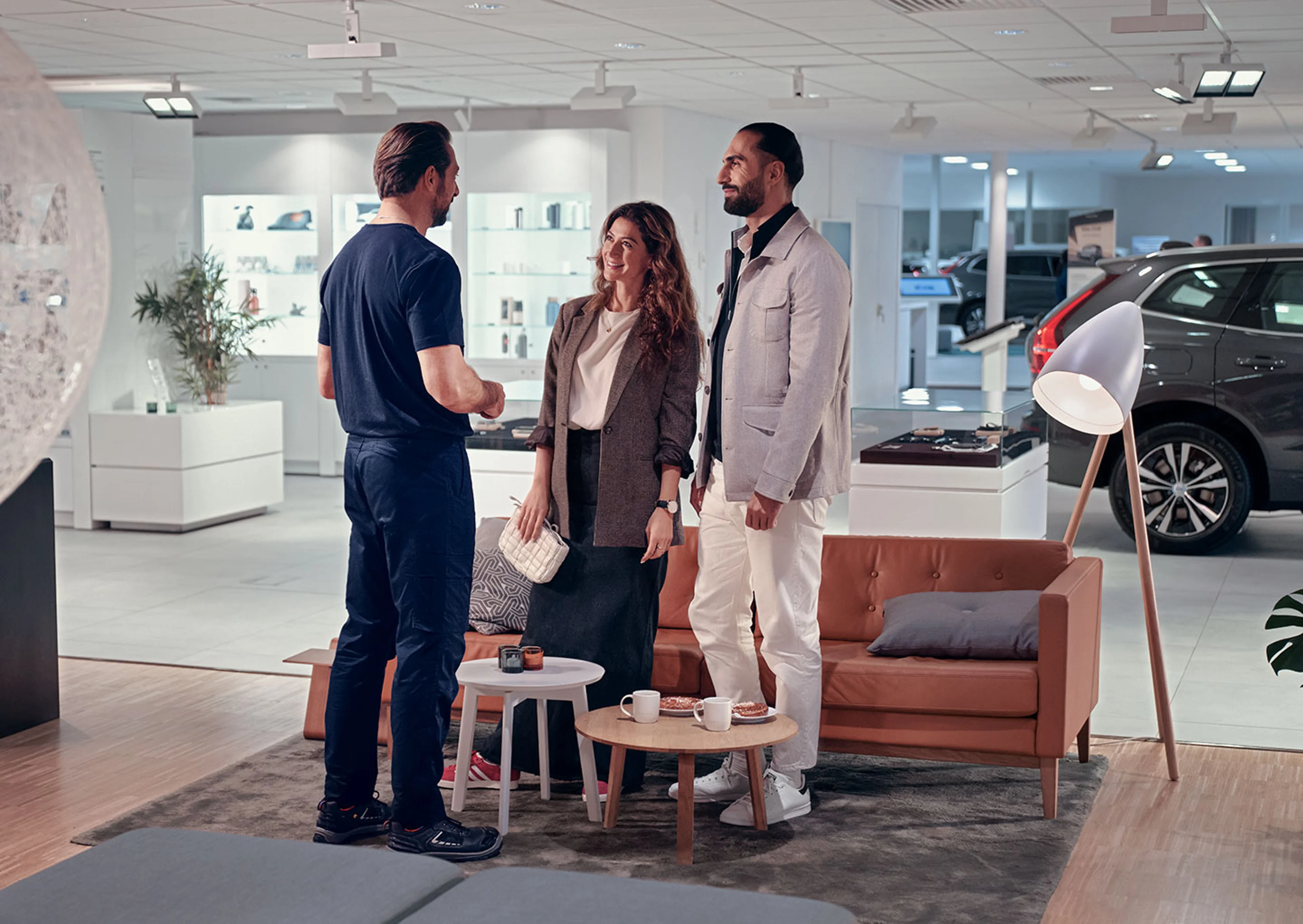 En servicetekniker ses bagfra, der snakker med to kunder i et showroom miljø