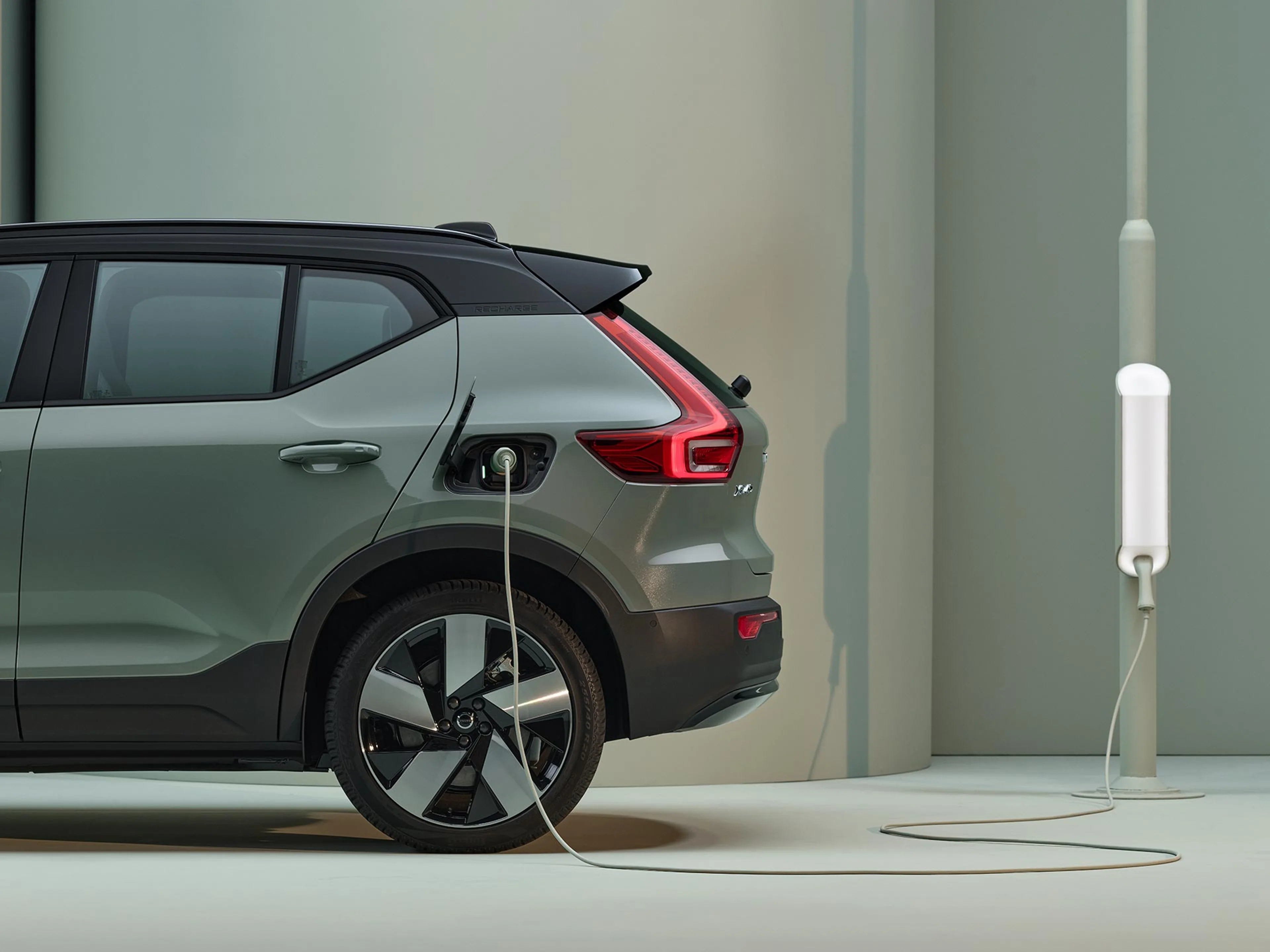 Ein salbeigrüner Volvo XC40 wird an einer Ladesäule geladen.