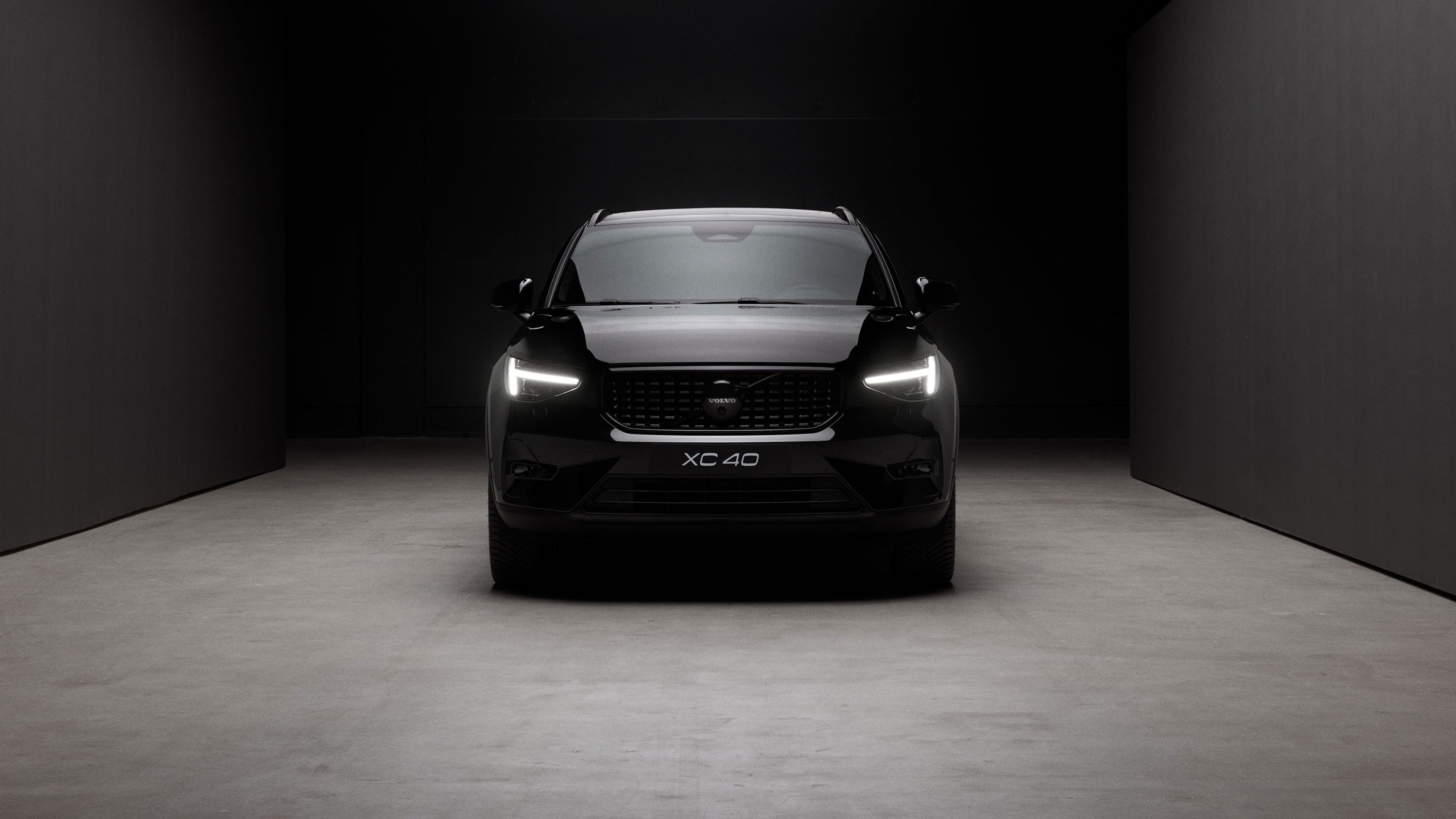 Vue avant du Volvo XC40 Black Edition, projecteurs LED allumés dans un environnement sombre