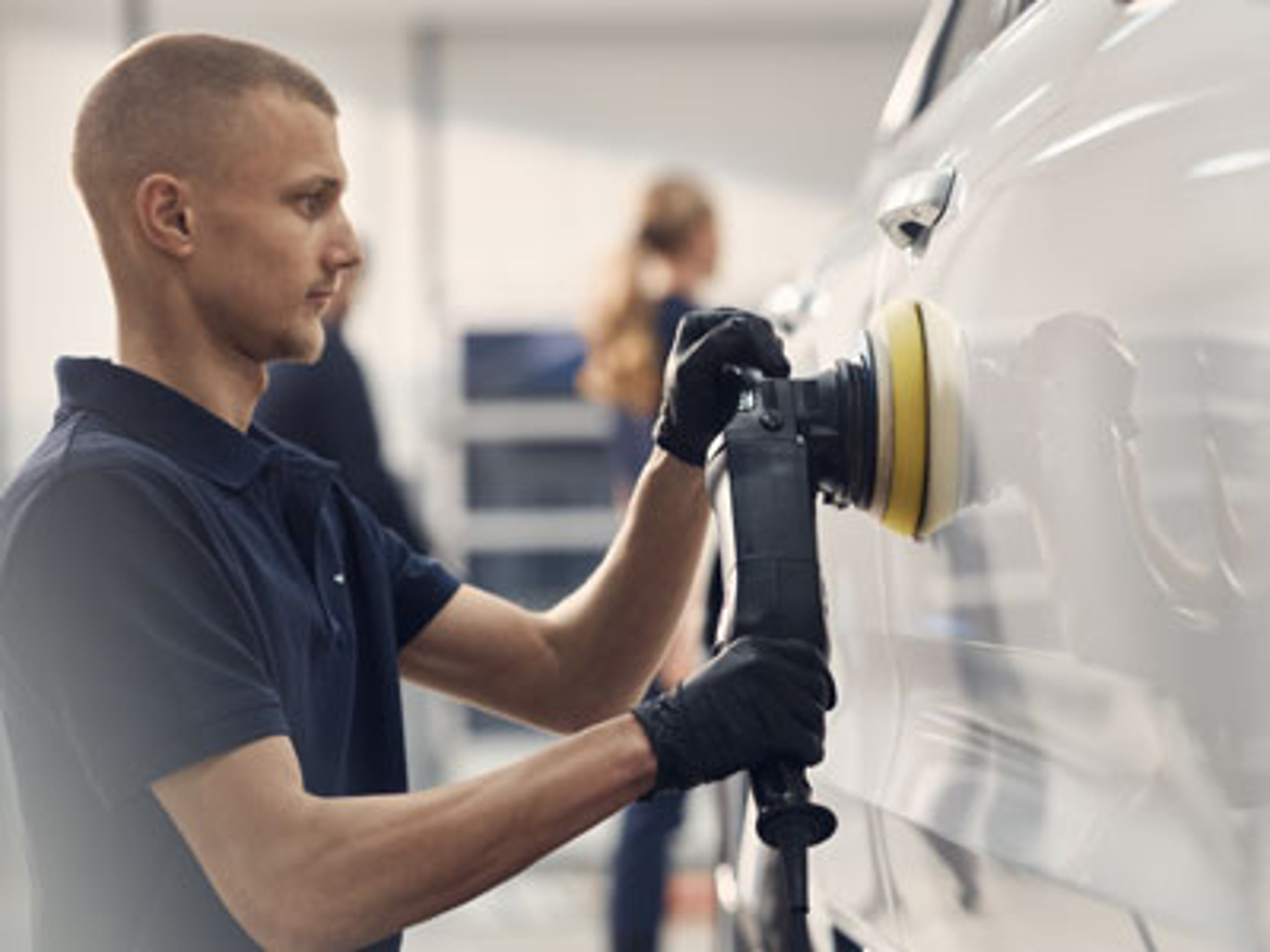 Mann polerer siden av en bil