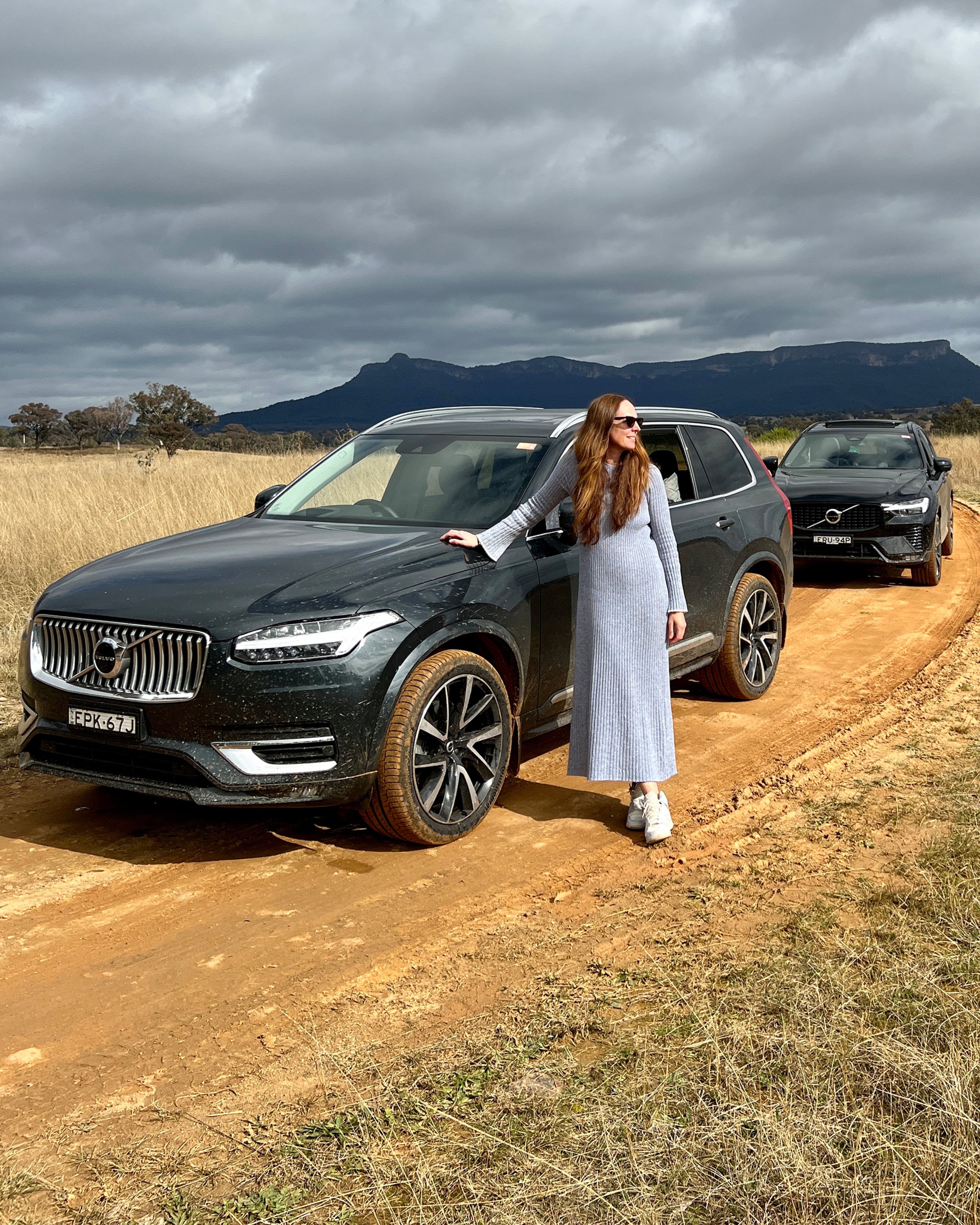 Person wearing dress leaning on car