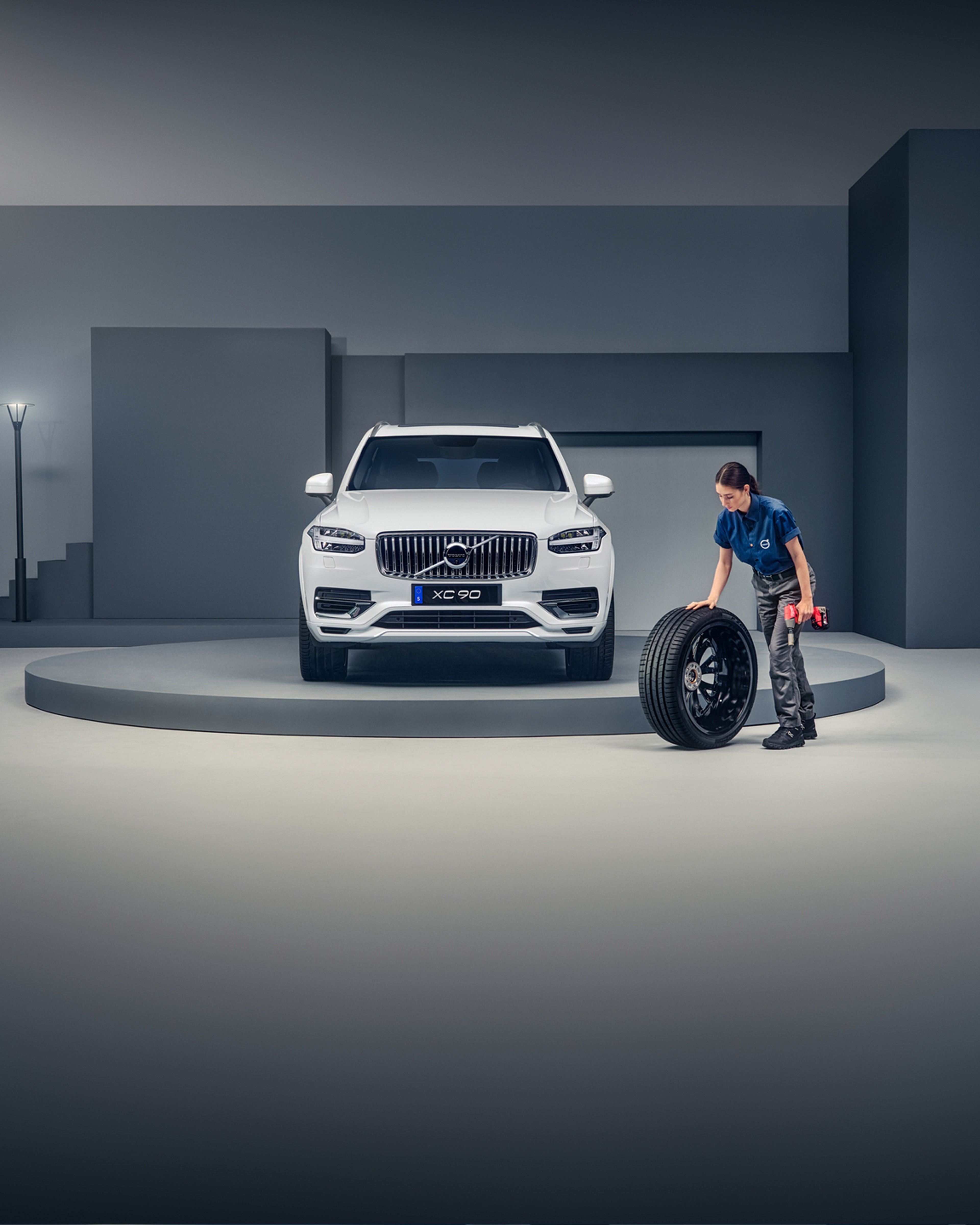 Kvinnelig Volvoansatt triller ett dekk i forbindelse med hjulskift på en hvit XC90