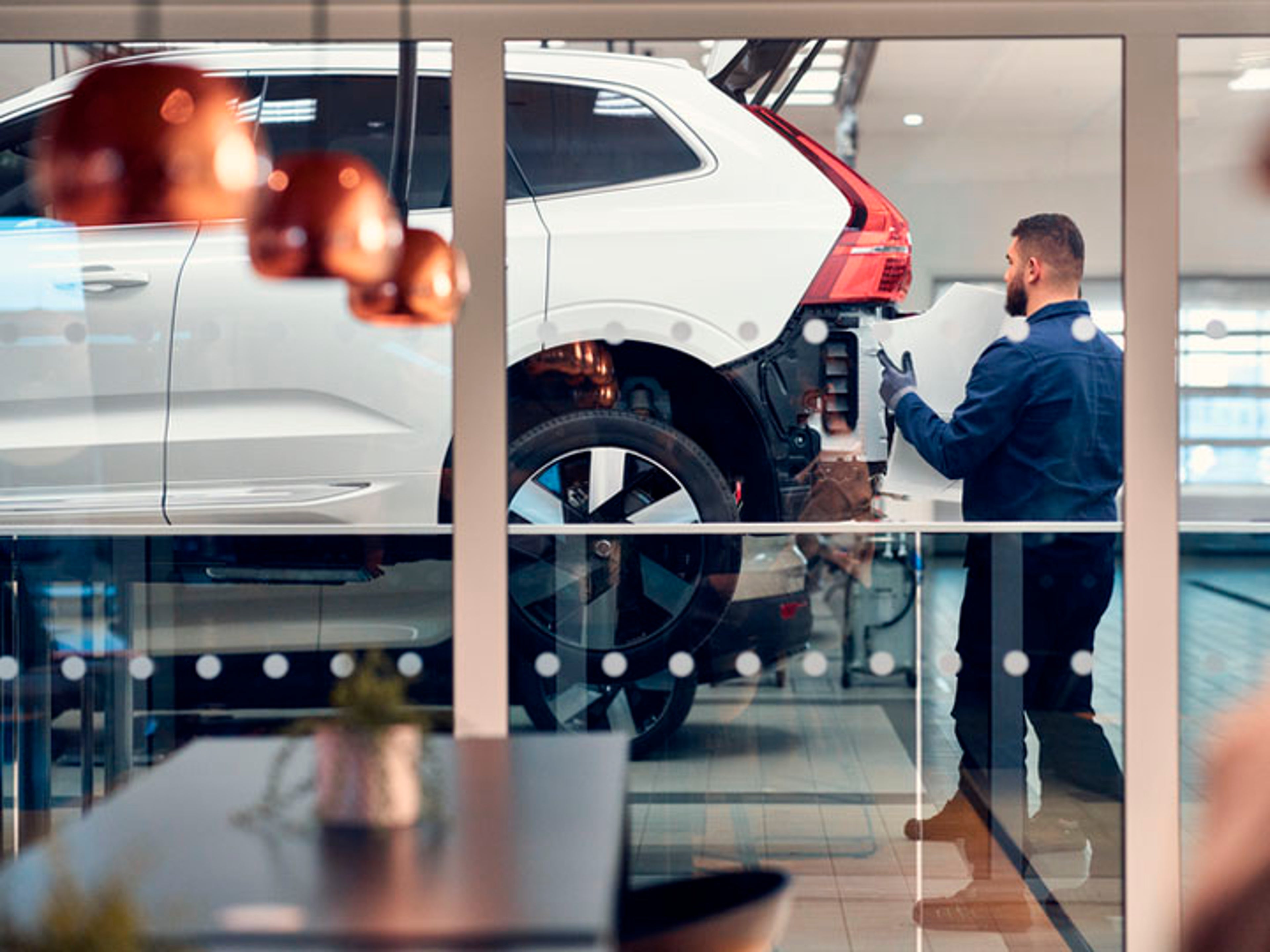 Un mecánico colocando una pieza en un vehículo SUV Volvo en un taller oficial