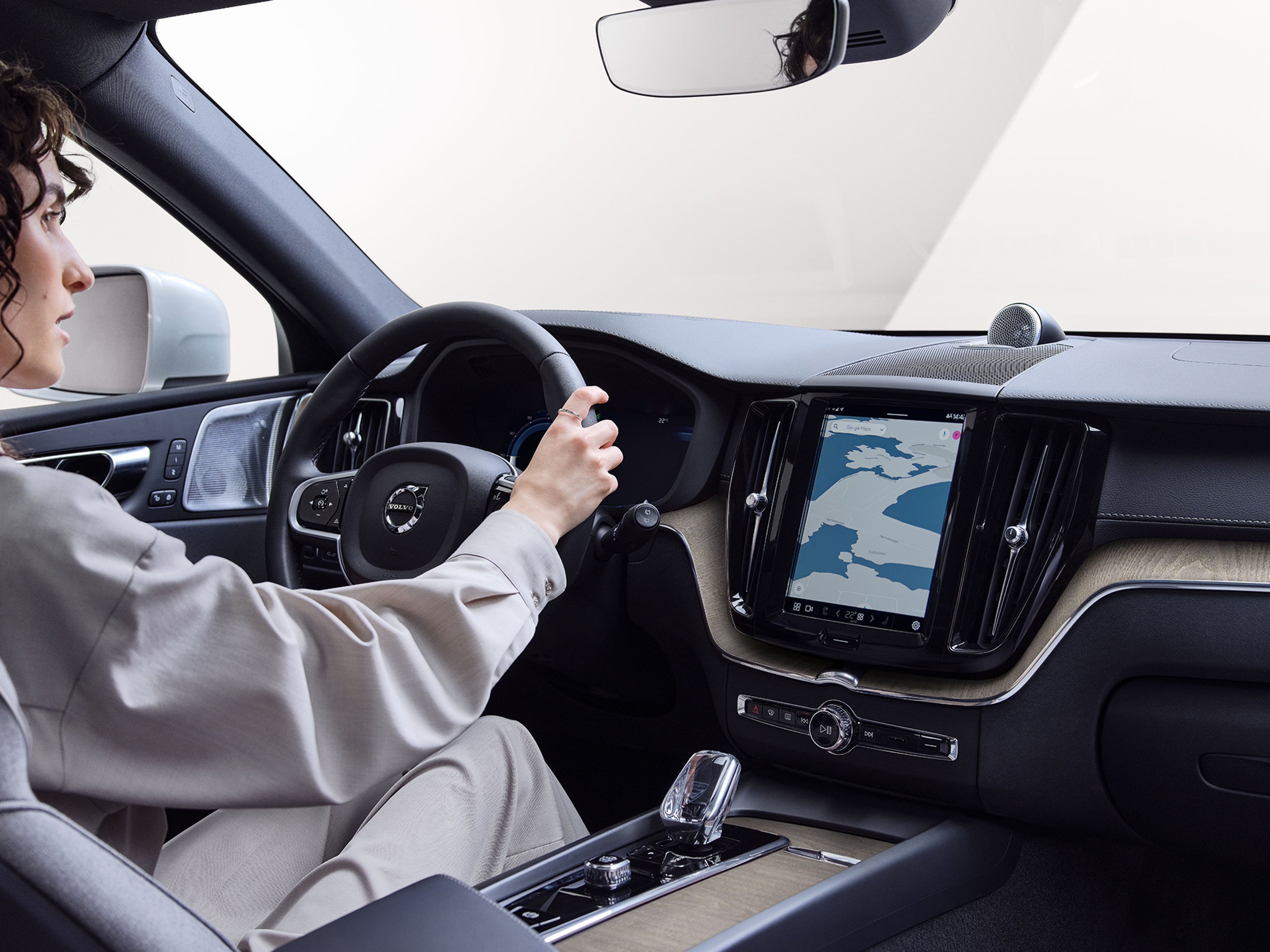 Mulher ao volante de um Volvo, com navegação por GPS exibida no tablet central.