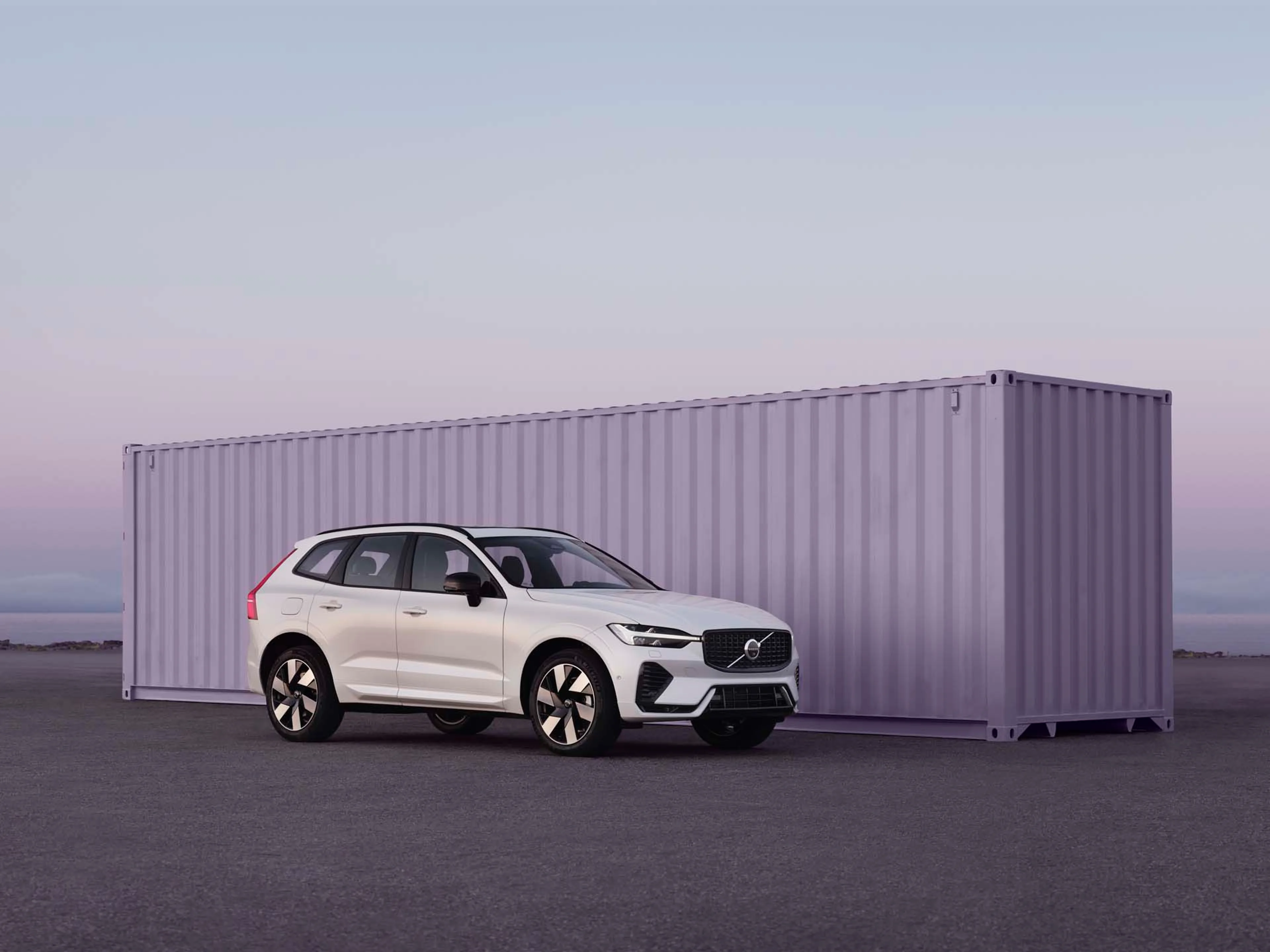 Volvo XC60 mild hybrid vista lateral delante de un container morado
