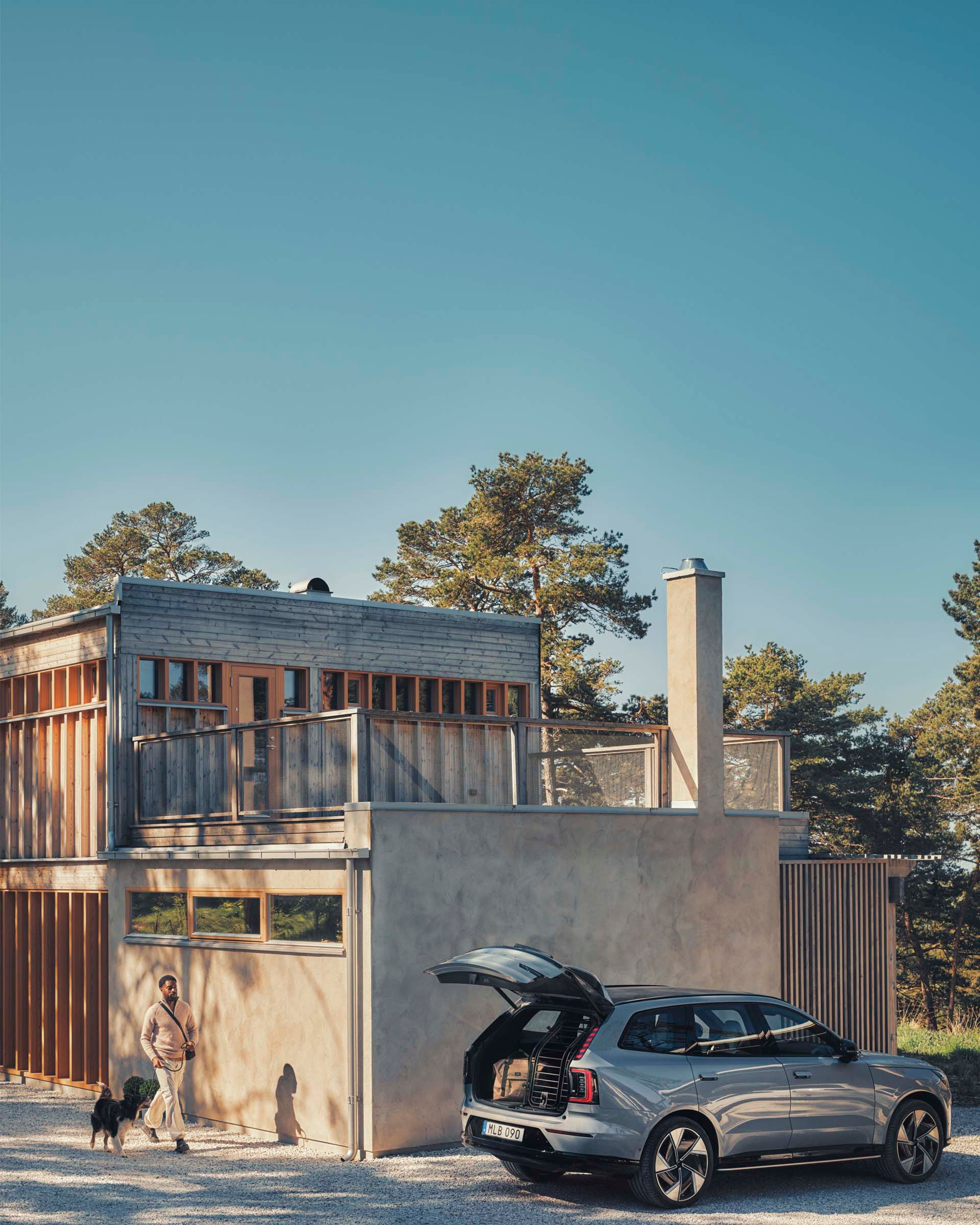 Volvo EX90 eléctrico y un hombre y su mascota dirigiéndose al vehículo