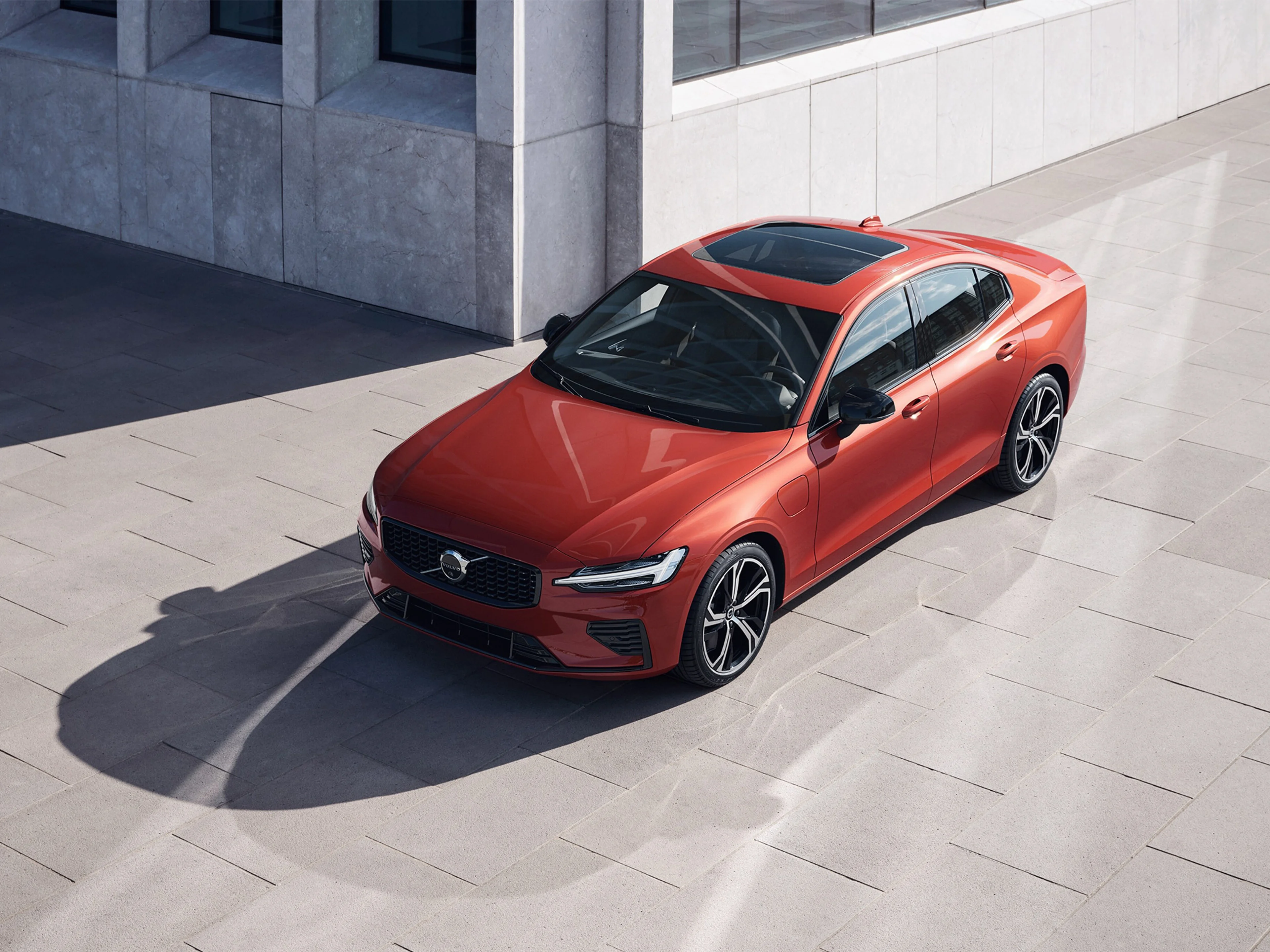 Fusion Red -värinen Volvo S60 Recharge Long Range Sport Edition lataushybridi etuyläviistosta kuvattuna.