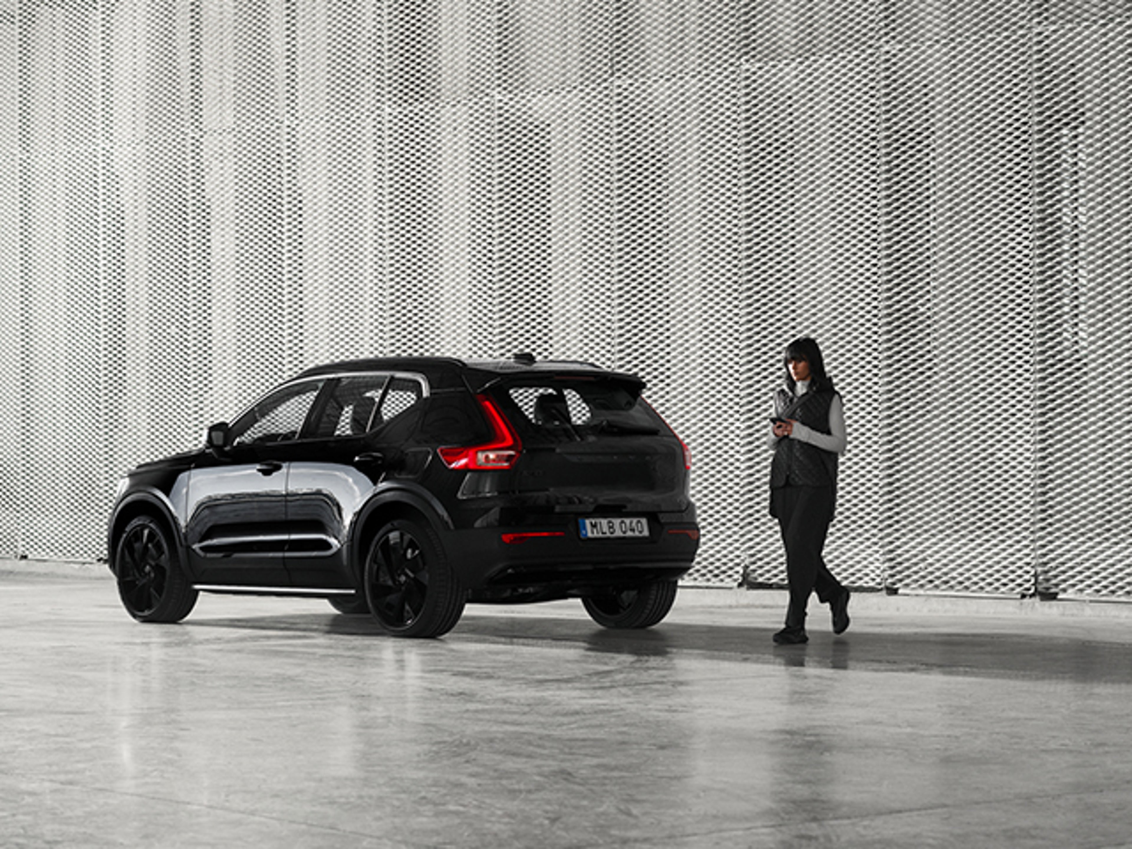 Kvinna står vid en Volvo EX40 black edition
