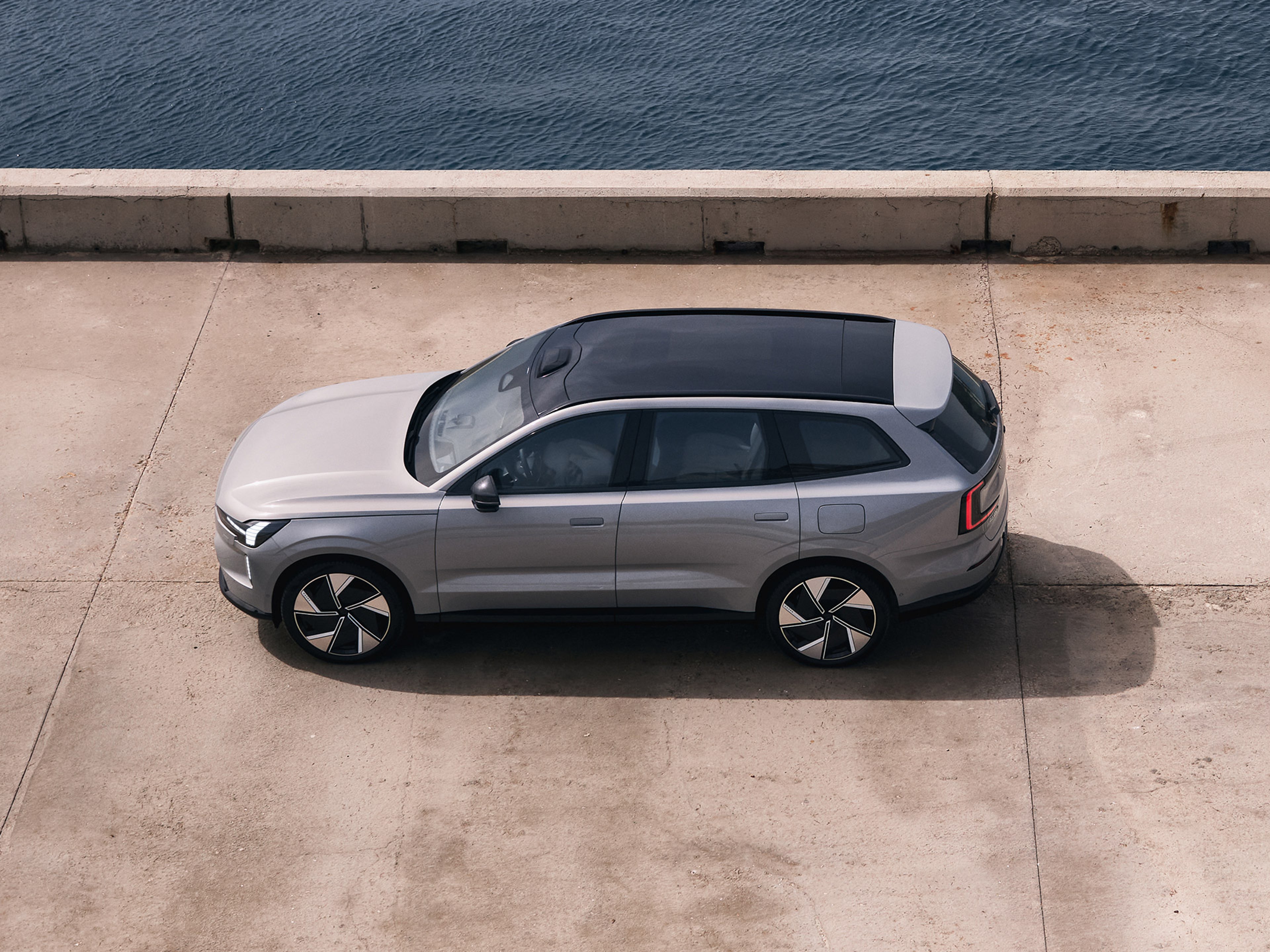 Vapour grey -värinen Volvo EX90 täyssähköauto pysäköitynä betonilaiturille.