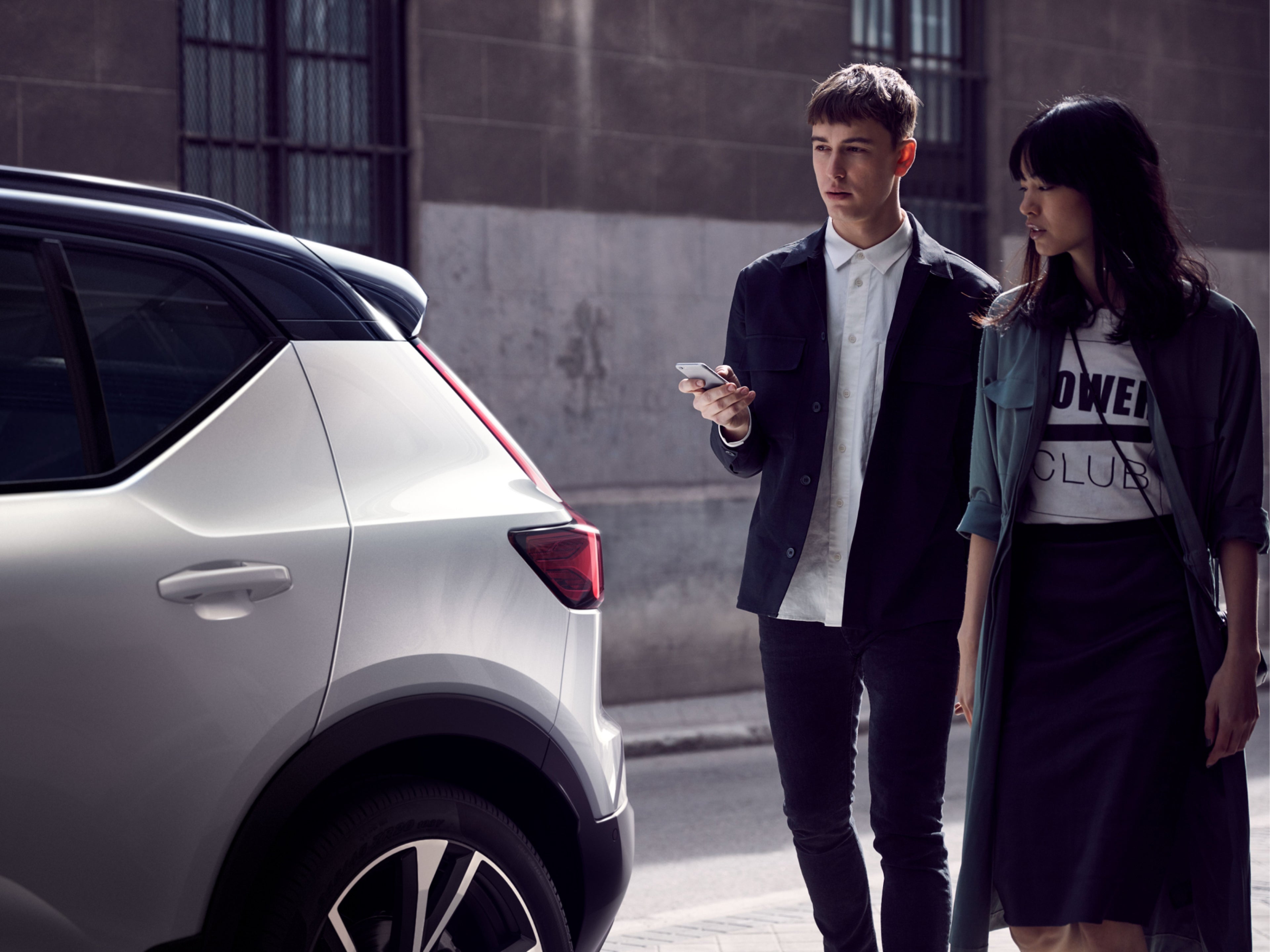 Un hombre y una mujer parados al lado de un Volvo XC40 blanco.