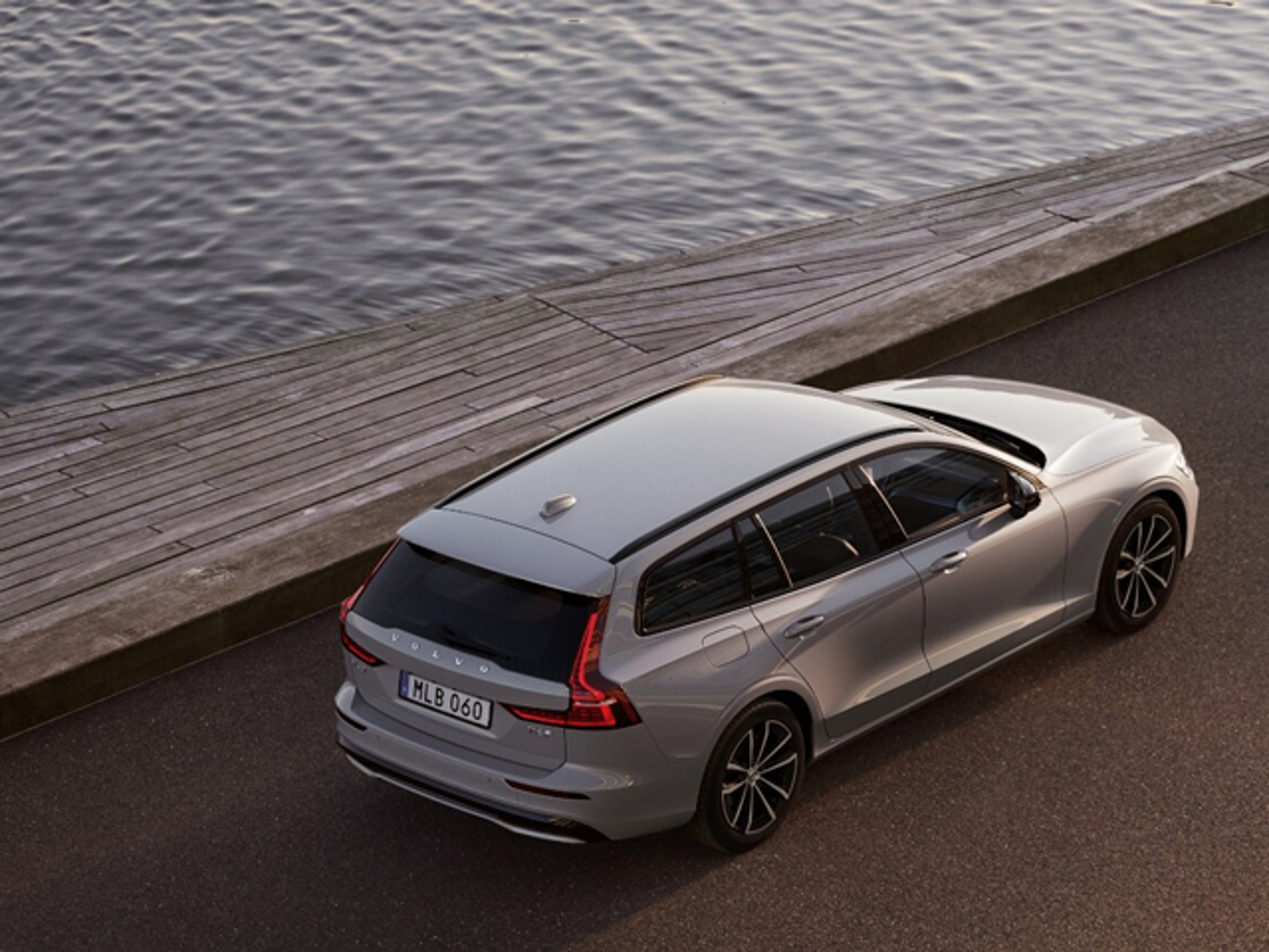 Silvrig Volvo V60 snett från sidan som står vid havet.