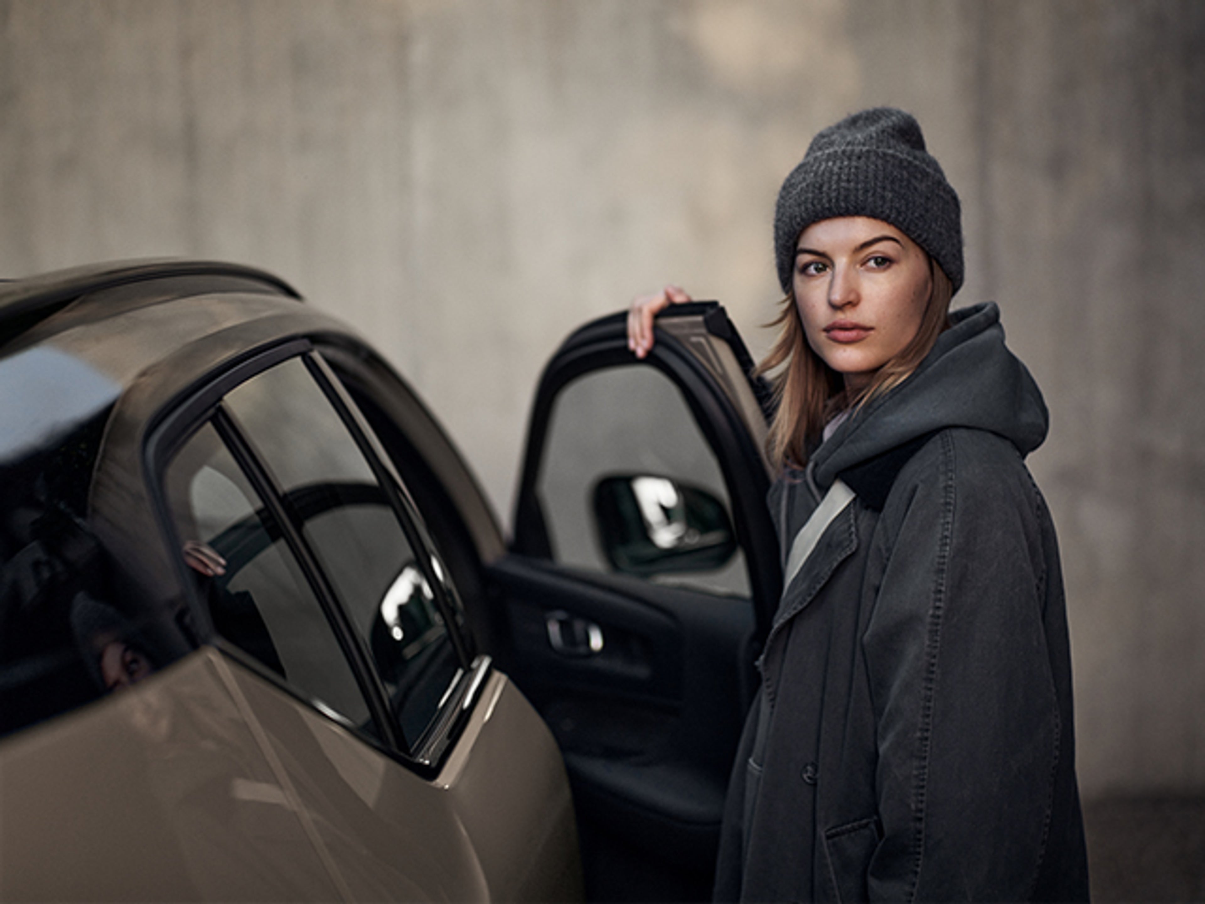 Kvinna står vid en öppen bildörr på en svart Vovo EX40