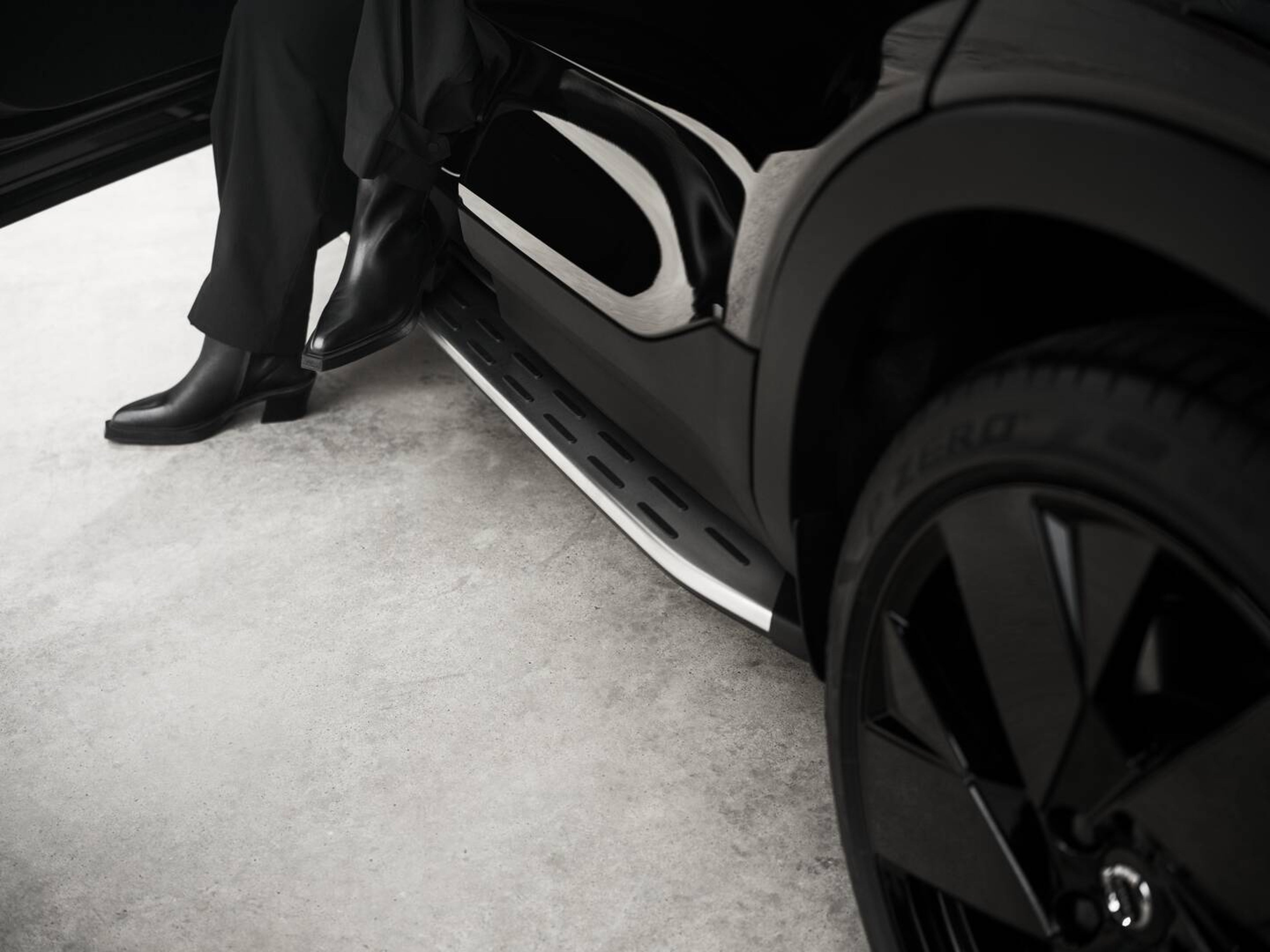 Closeup of black trousered person stepping out of Volvo car over a silver running board