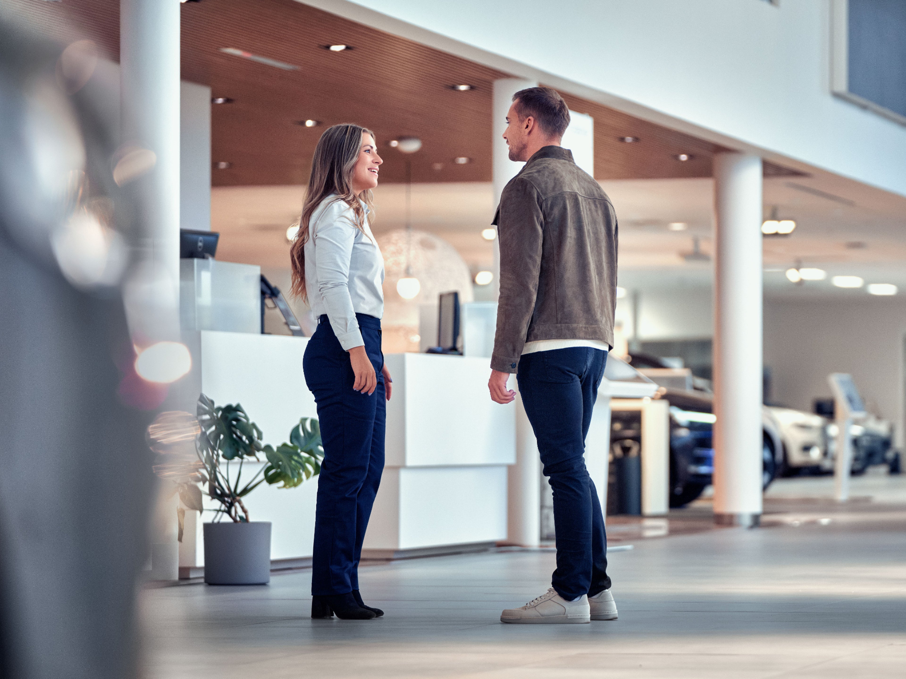 Eine Frau und ein Mann unterhalten sich in einem Autohaus.