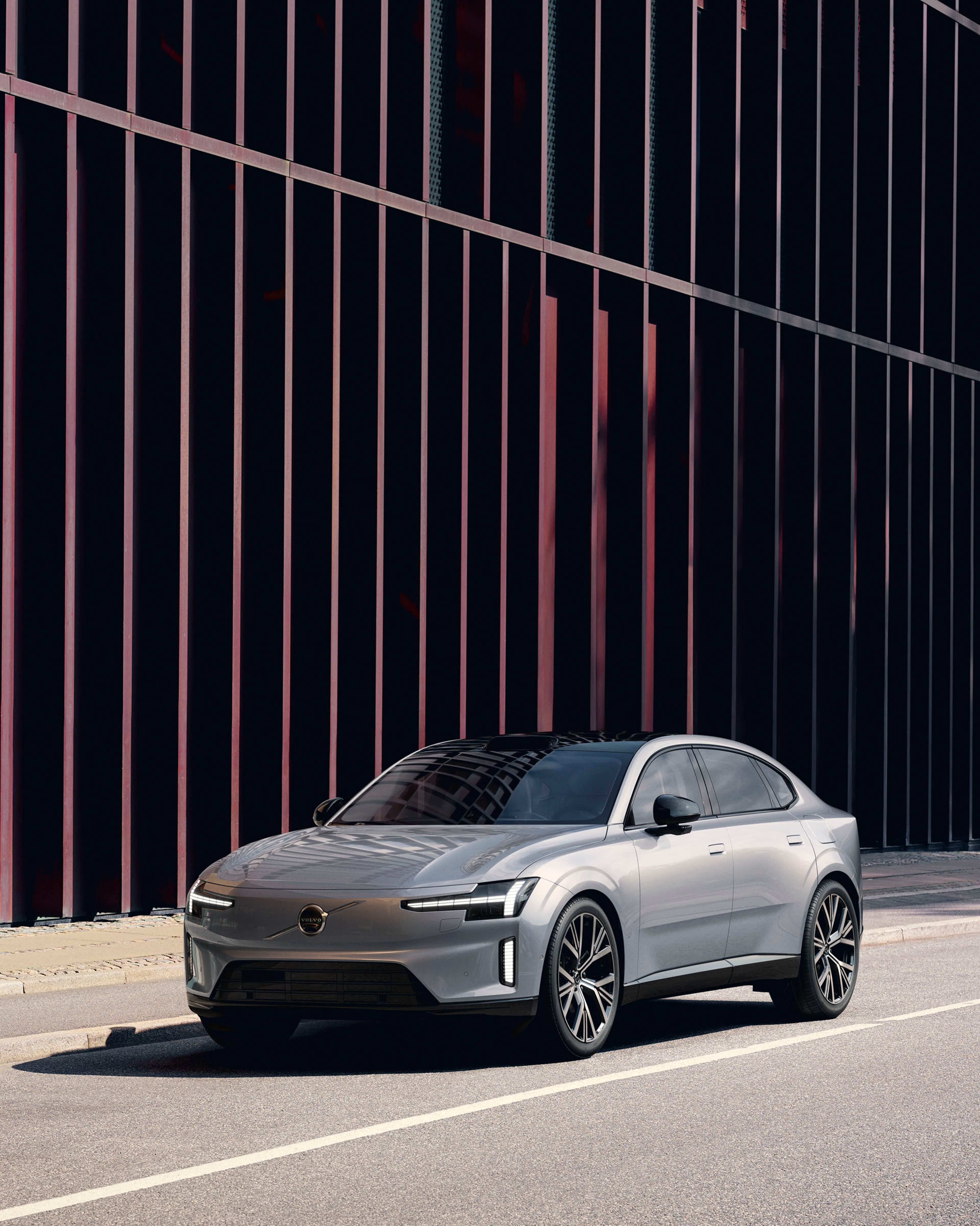 Un Volvo ES90 vista frontal lateral en color gris metalizado destacando sus llantas y su logo central.