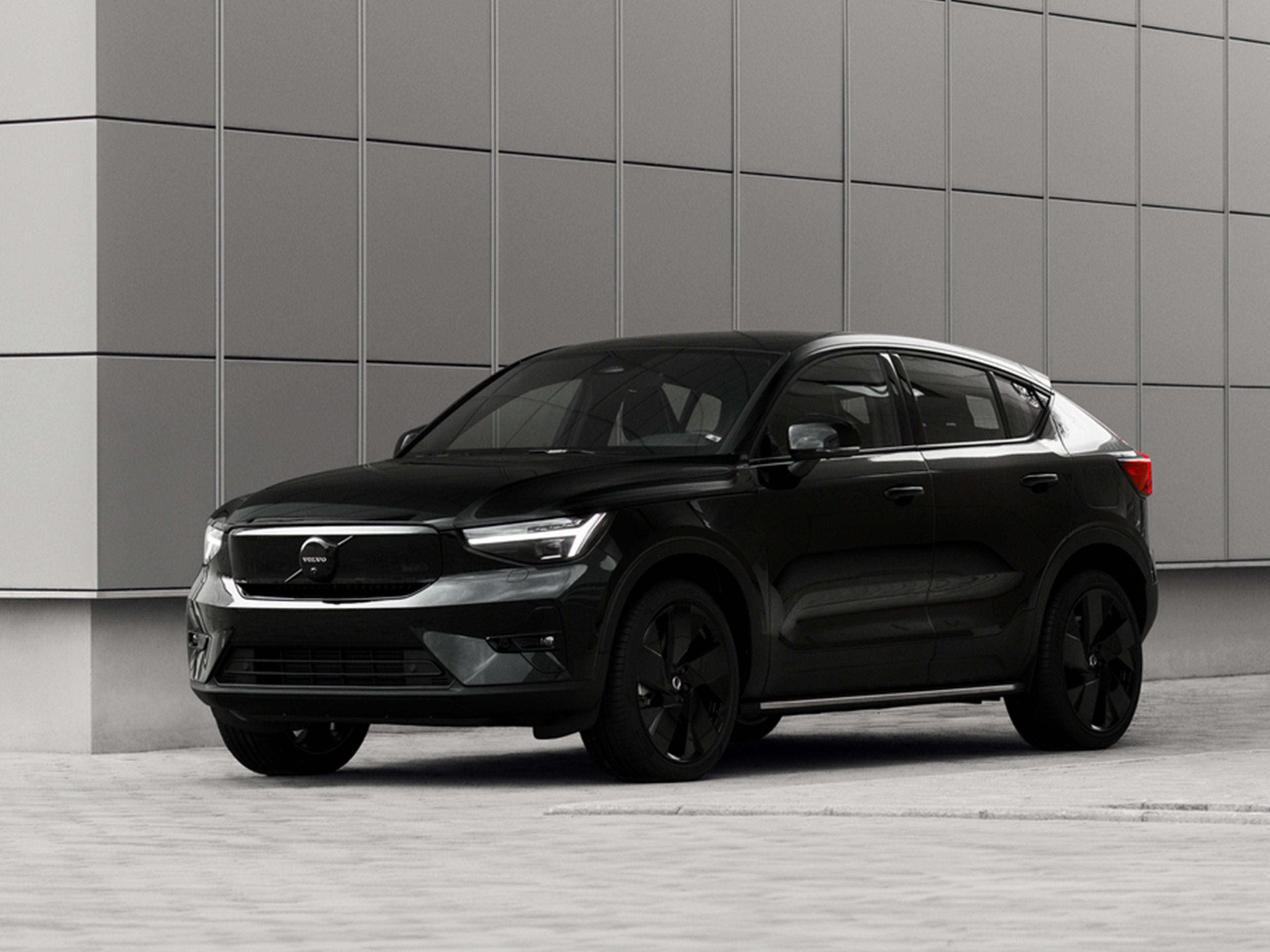 Volvo EC40 Black Edition auto harmaata, laatoitettua seinää vasten.