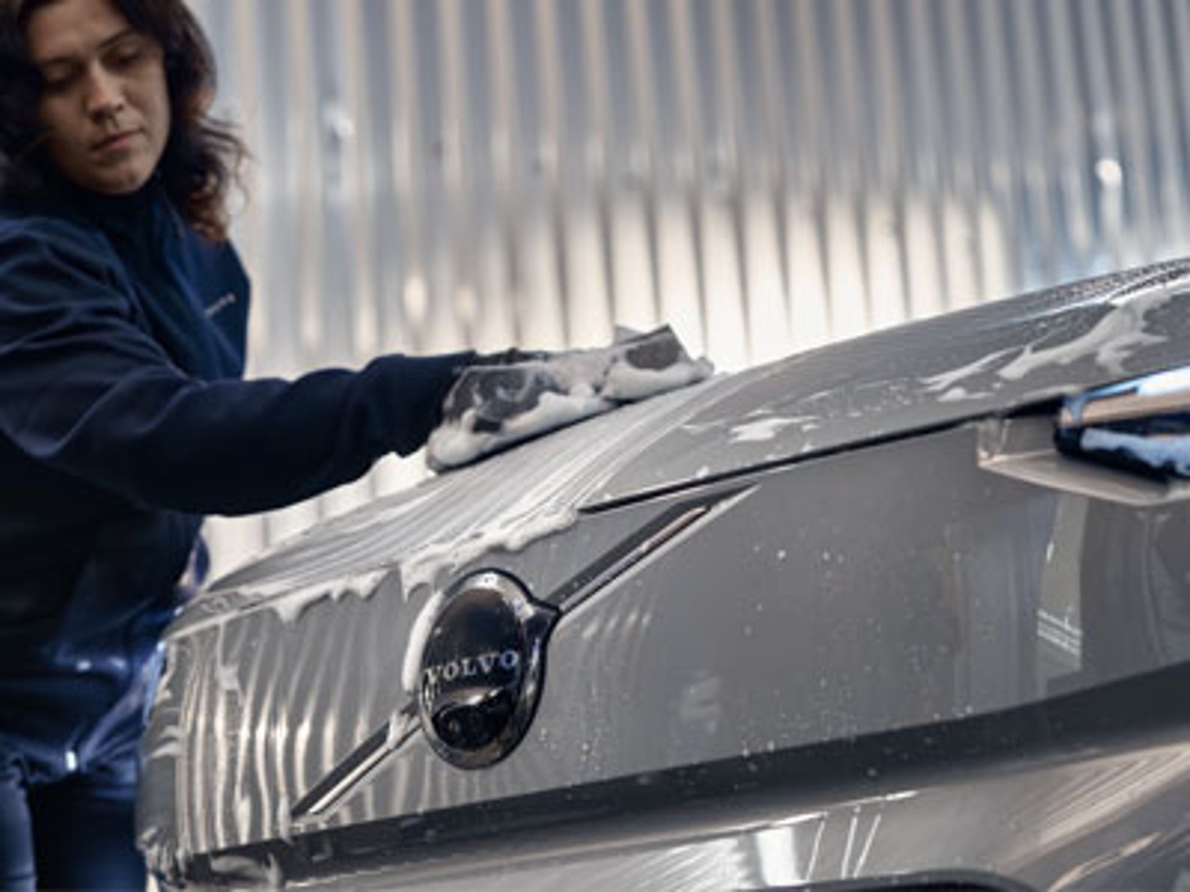 En hånd som vasker panseret på en lys Volvo