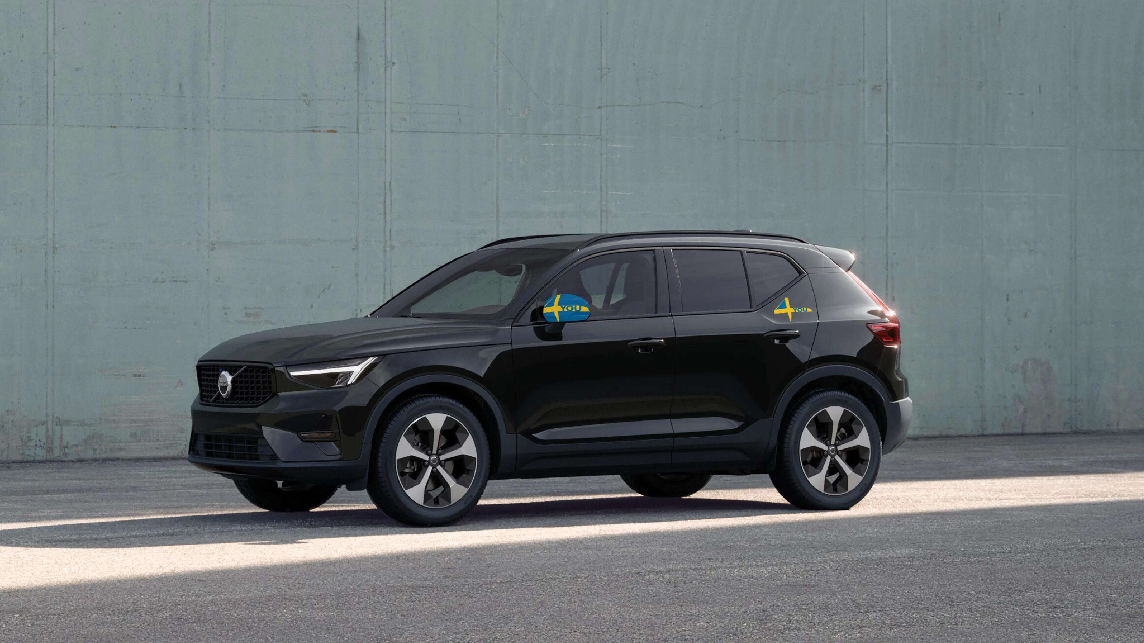 Ein schwarzer Volvo XC40 in der Sonderedition steht vor einer grünen Wand.