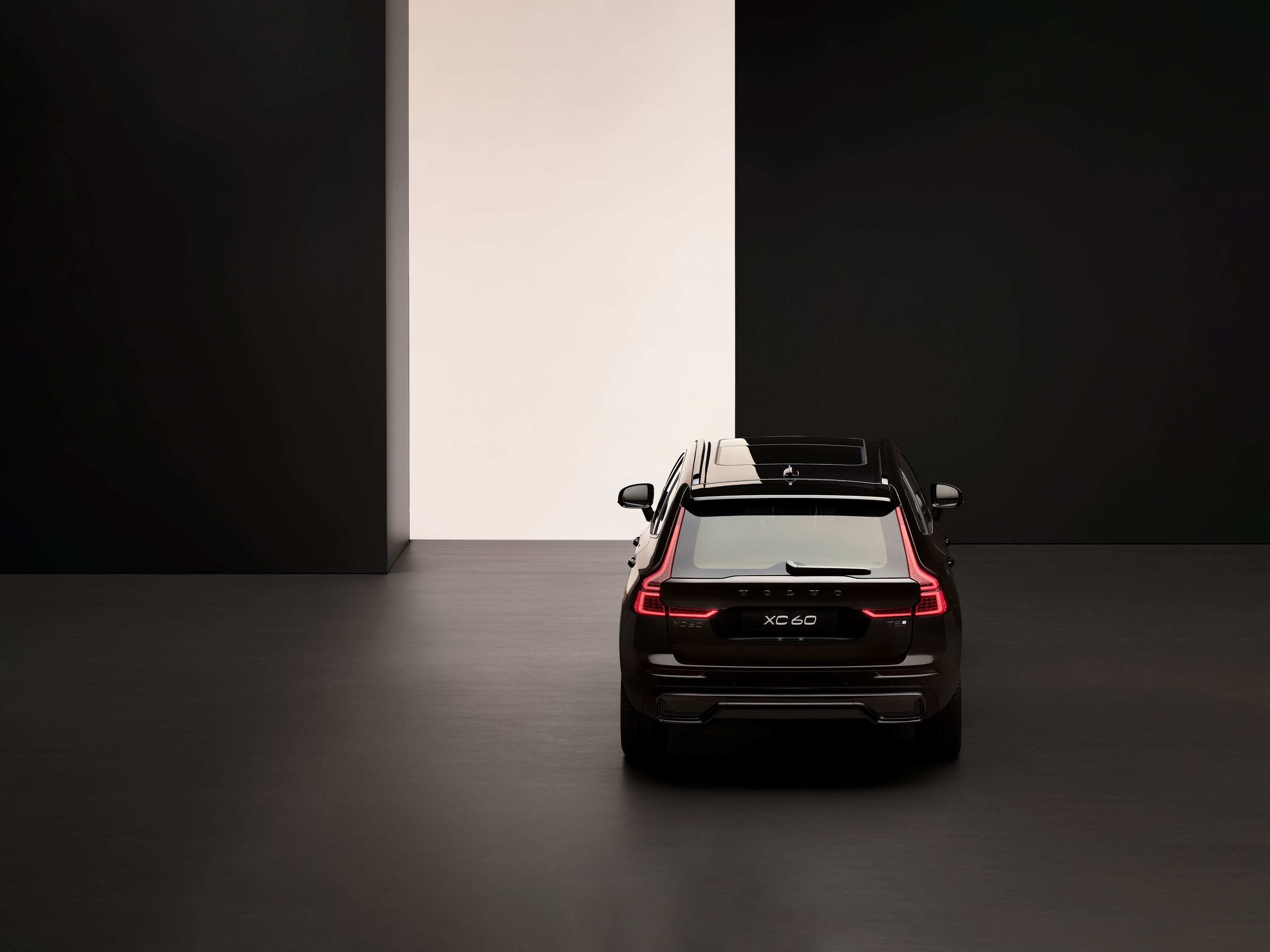 Ein tiefschwarzer Volvo XC60 SUV steht in einem dunklen Raum, in mit wenig Licht.