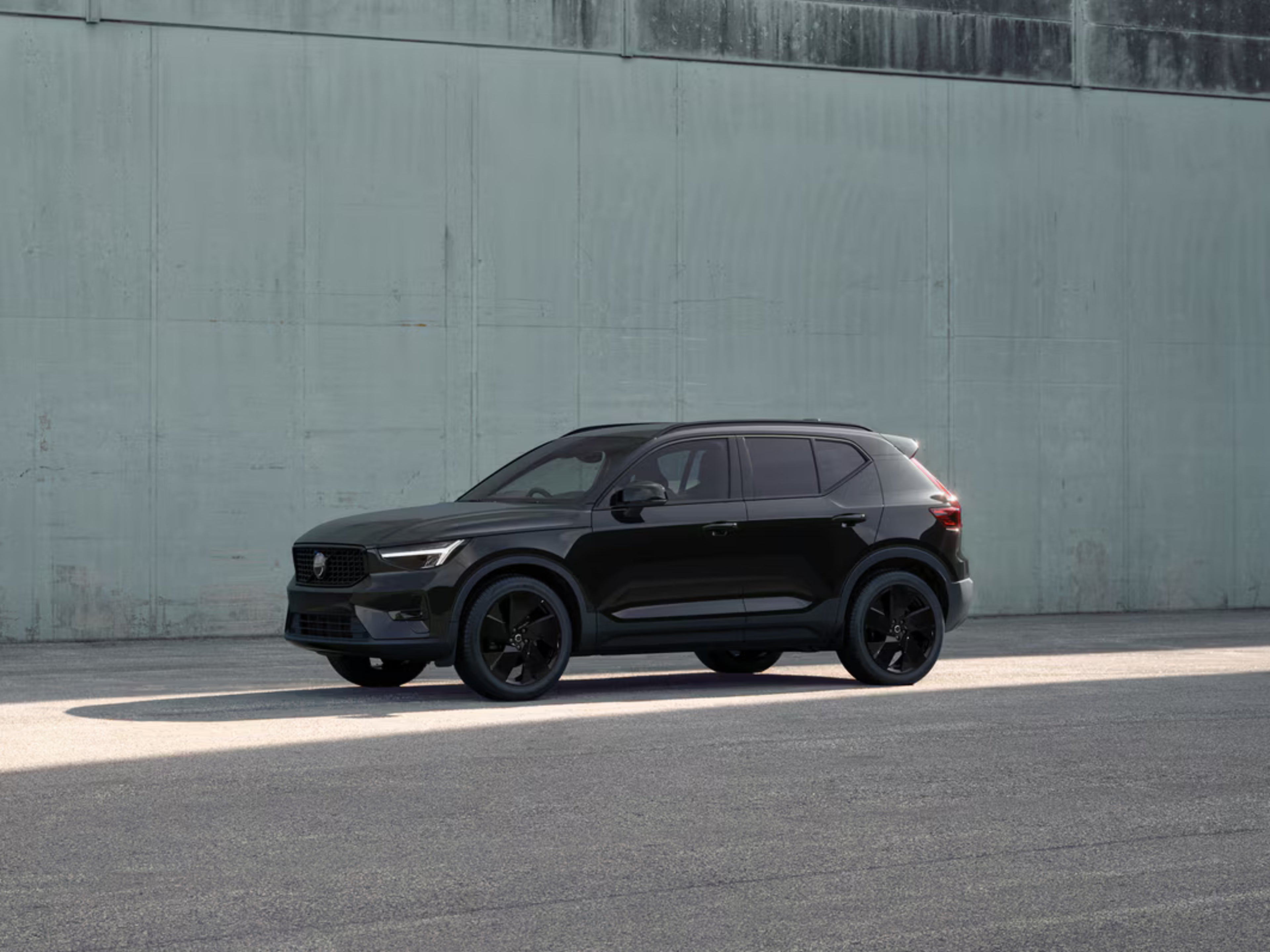 Side view of XC40 in front of concrete wall in sunlight