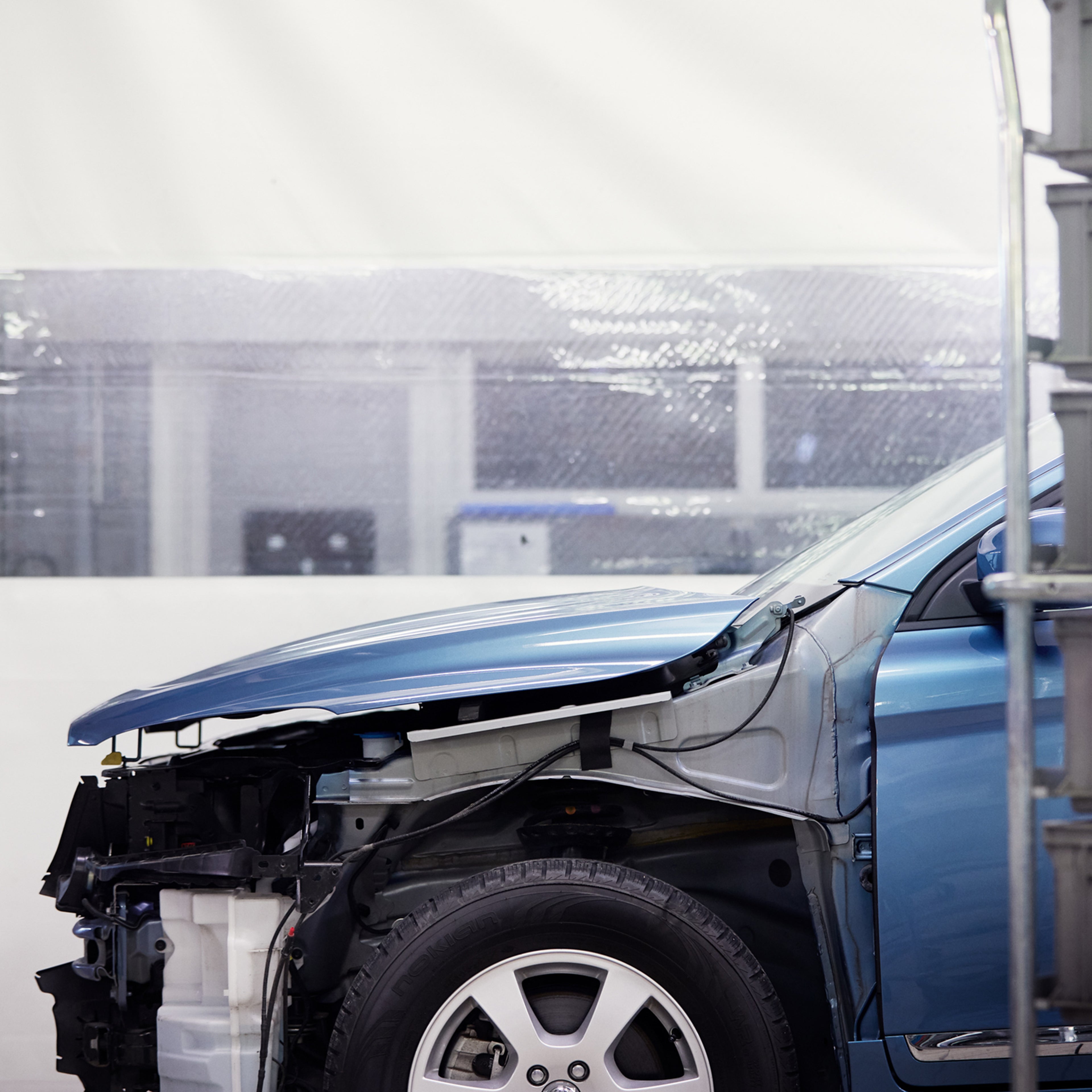 Vauriokorjaamolle tuotu sininen auto, josta on irroitettu etulokasuoja.