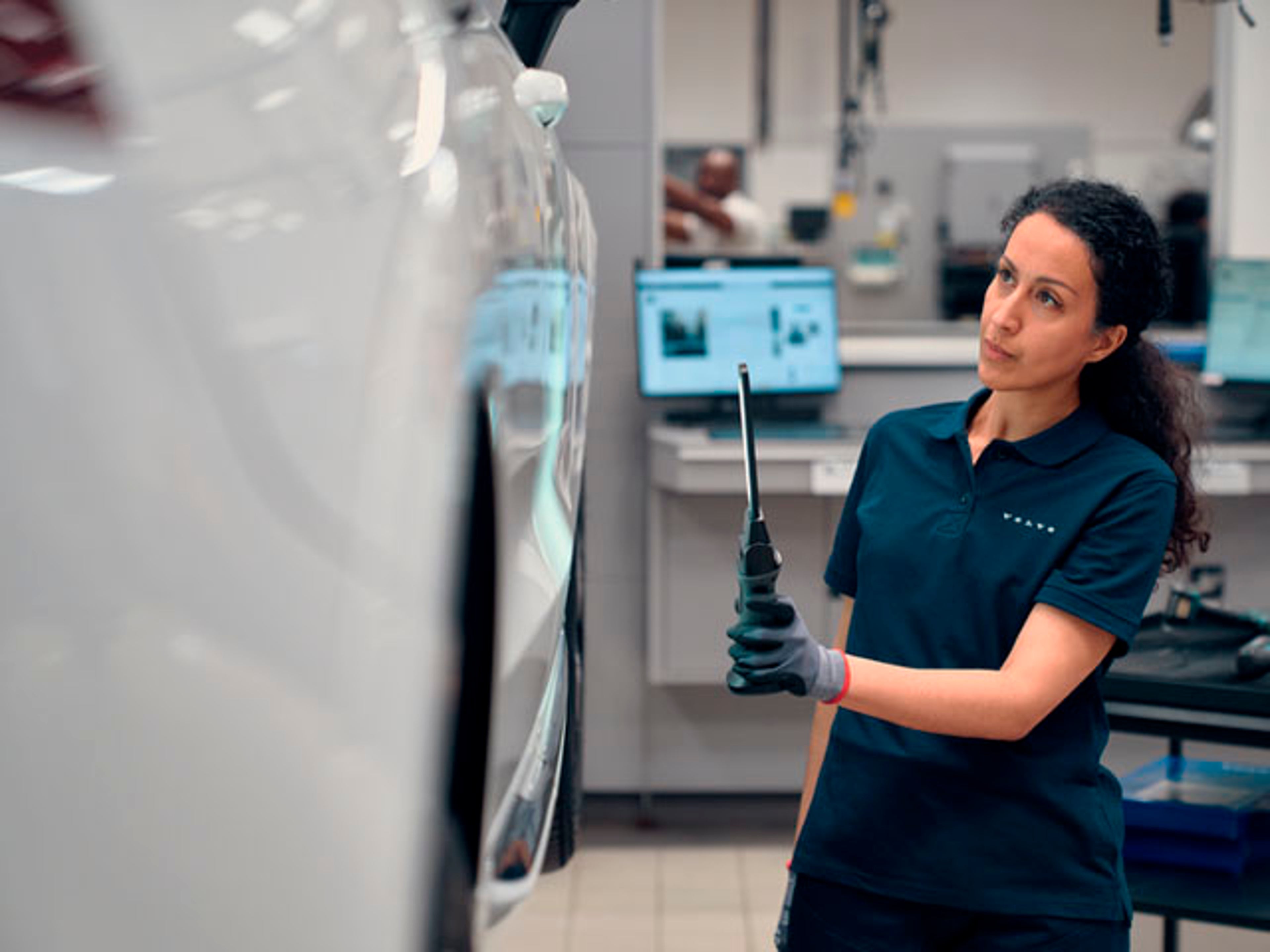 Una mujer en un taller Volvo haciendo un chequeo a un vehículo Volvo
