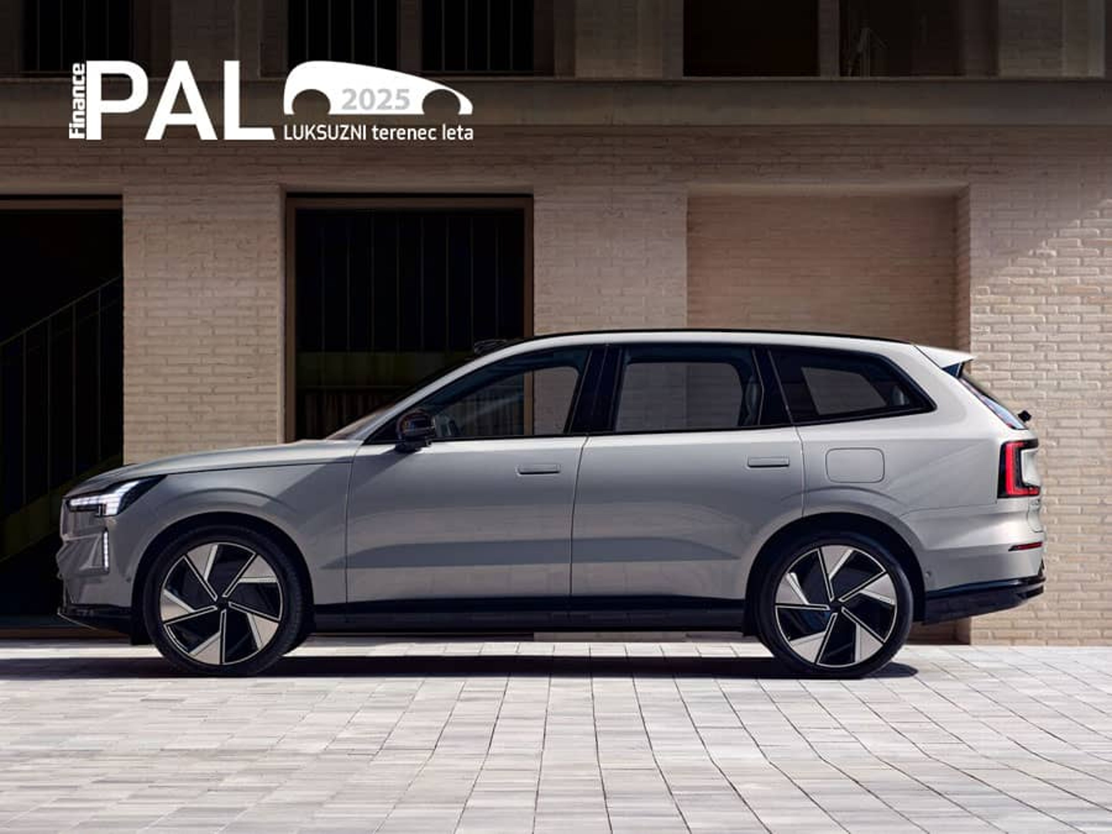 Srebrni luksuzni Volvo EX90 parkiran pred sodobno stavbo, prejemnik nagrade PAL 2025 za luksuzni terenec leta.