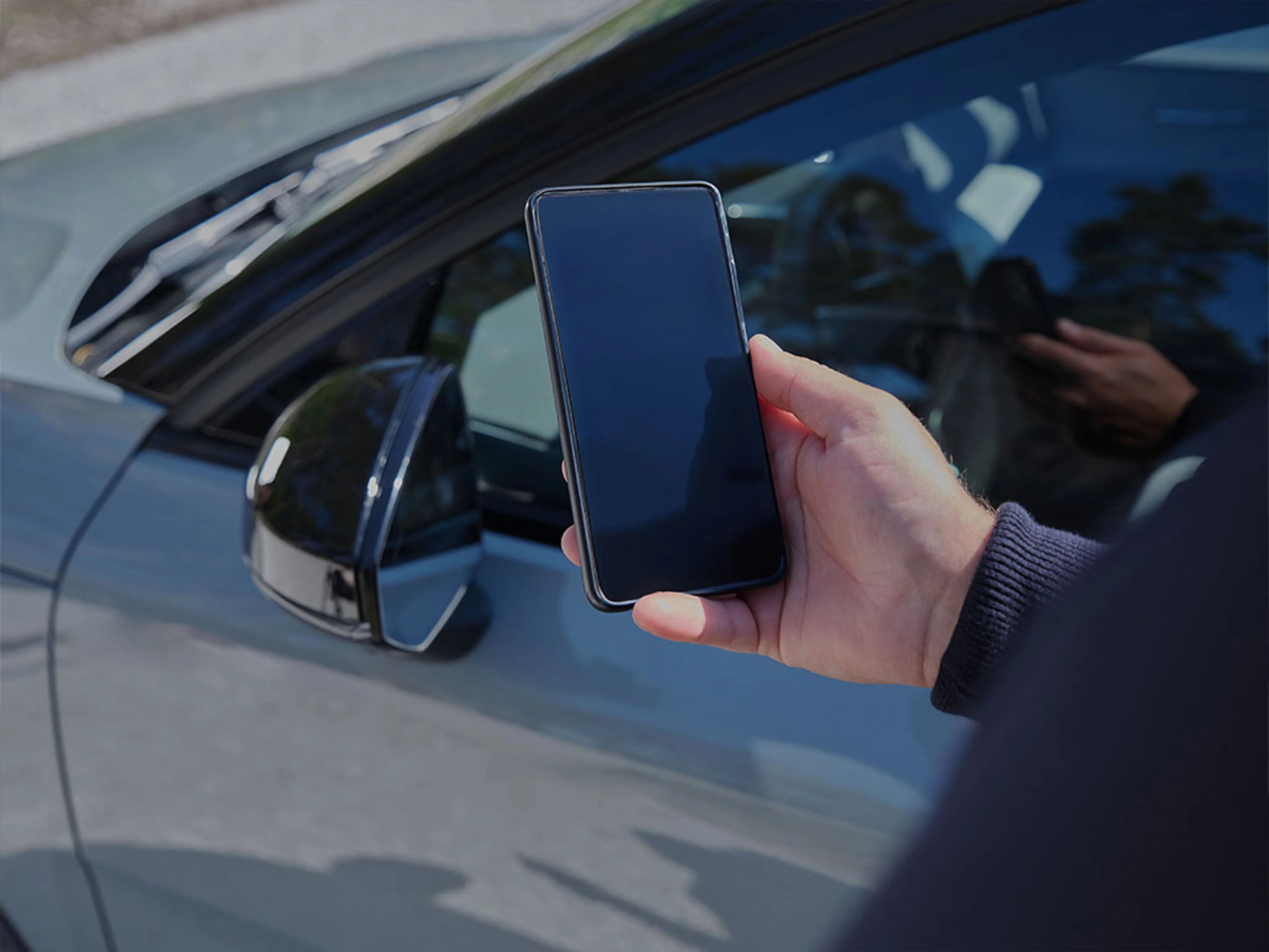 Personne tenant un smartphone devant une Volvo