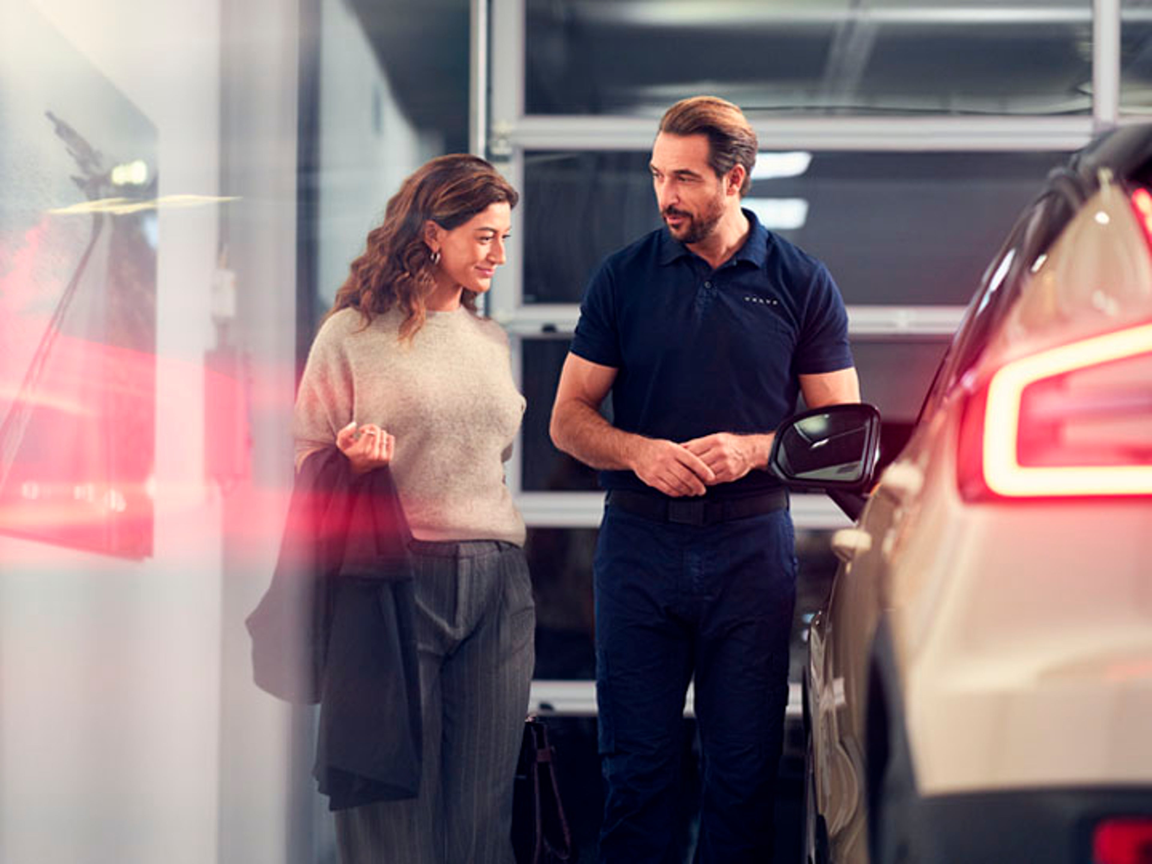 Un mecánico hablando con una cliente en un taller Volvo