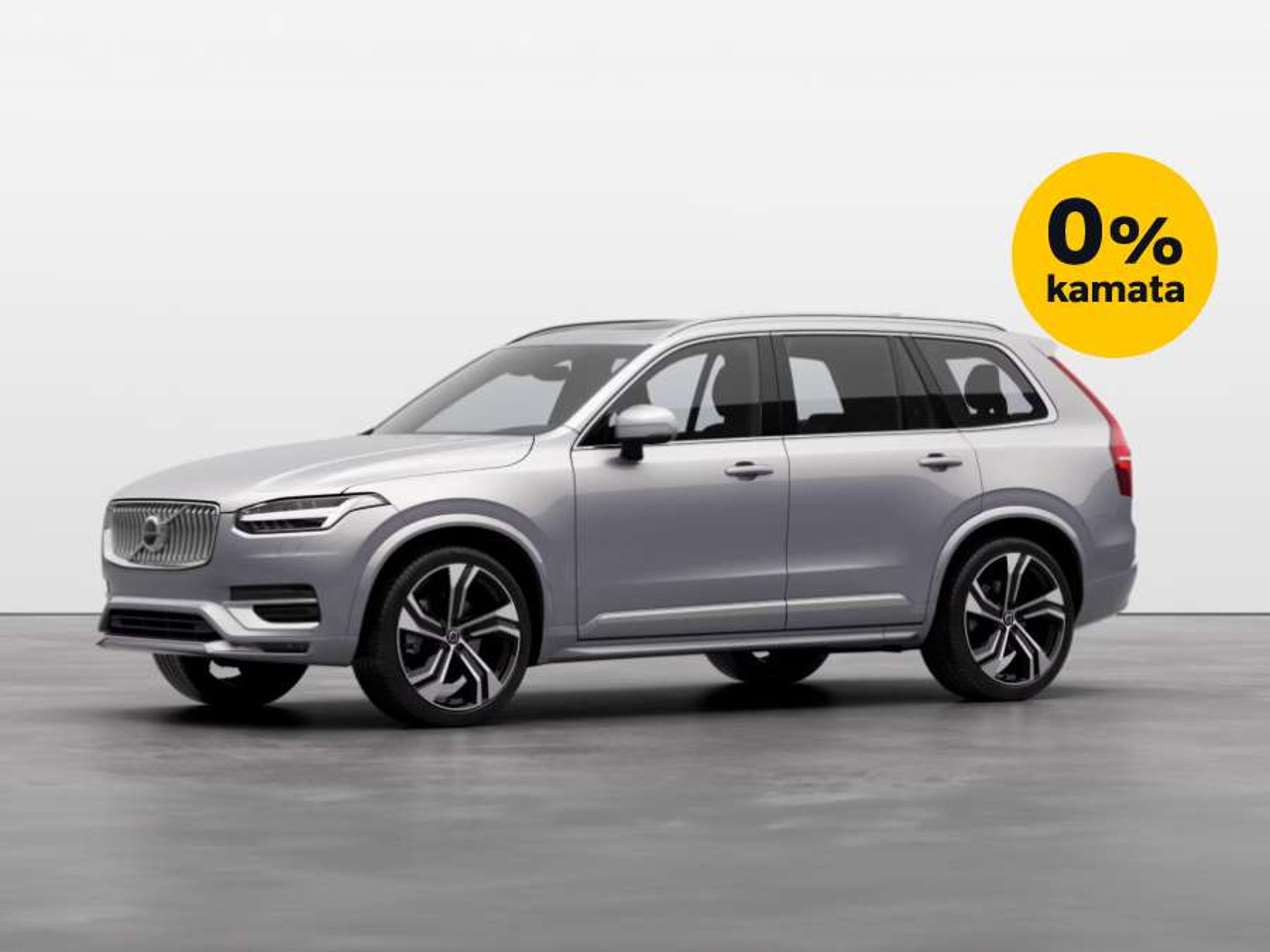 Srebrni Volvo XC90 parkiran u studijskom okruženju s bijelom pozadinom, uz oznaku '0% kamata' u žutom krugu u gornjem desnom kutu.