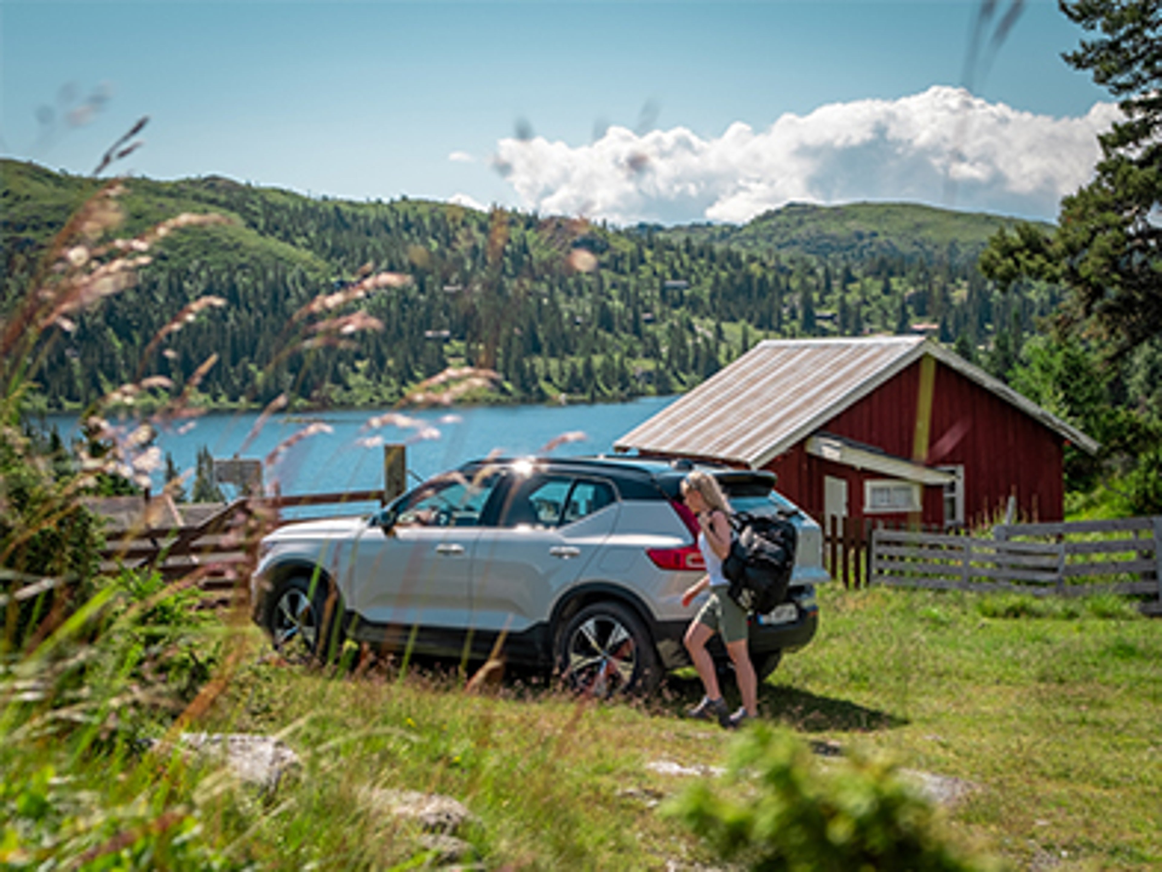 Woman in front of a XC40 on the country side with a lake in the background