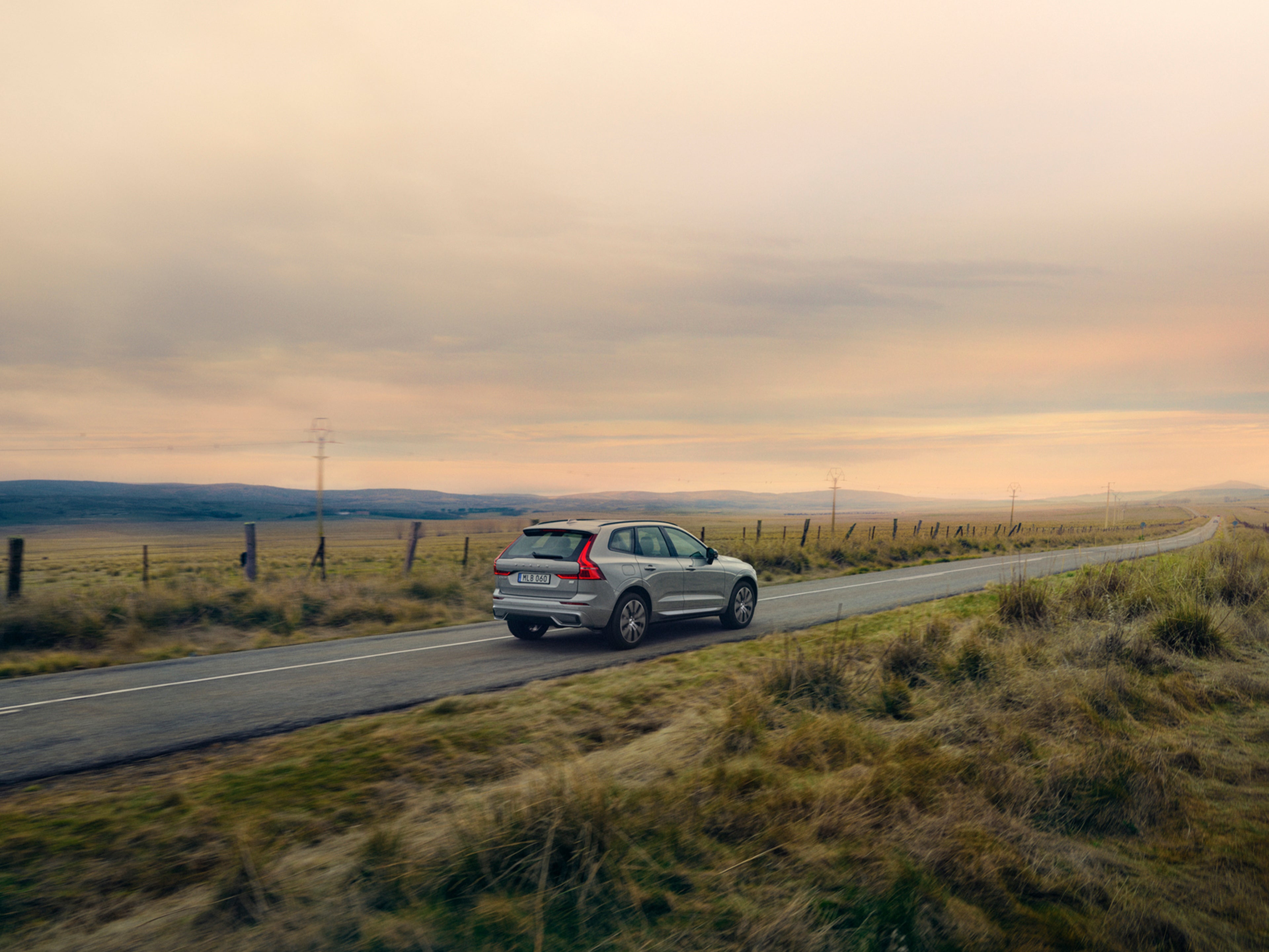 Un Volvo XC60 gris en una carretera con parajes a los lados.
