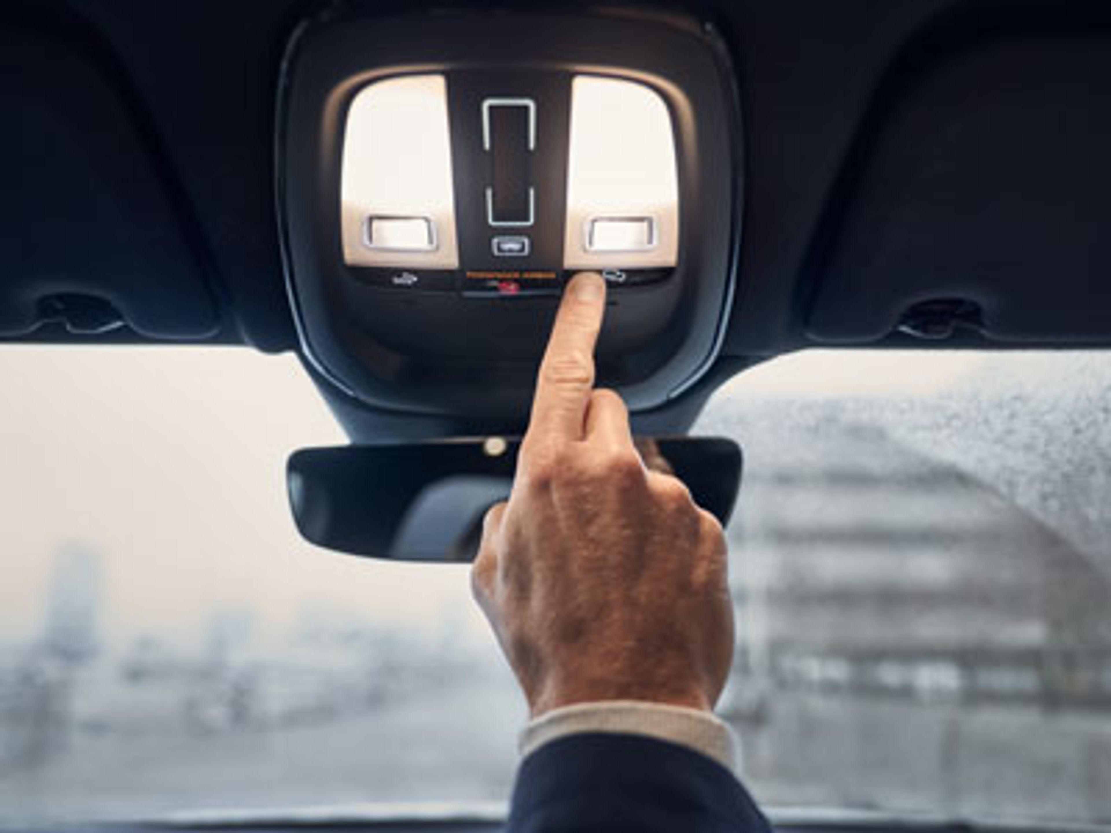 Hånd som trykker på On call knappen i taket på en Volvo