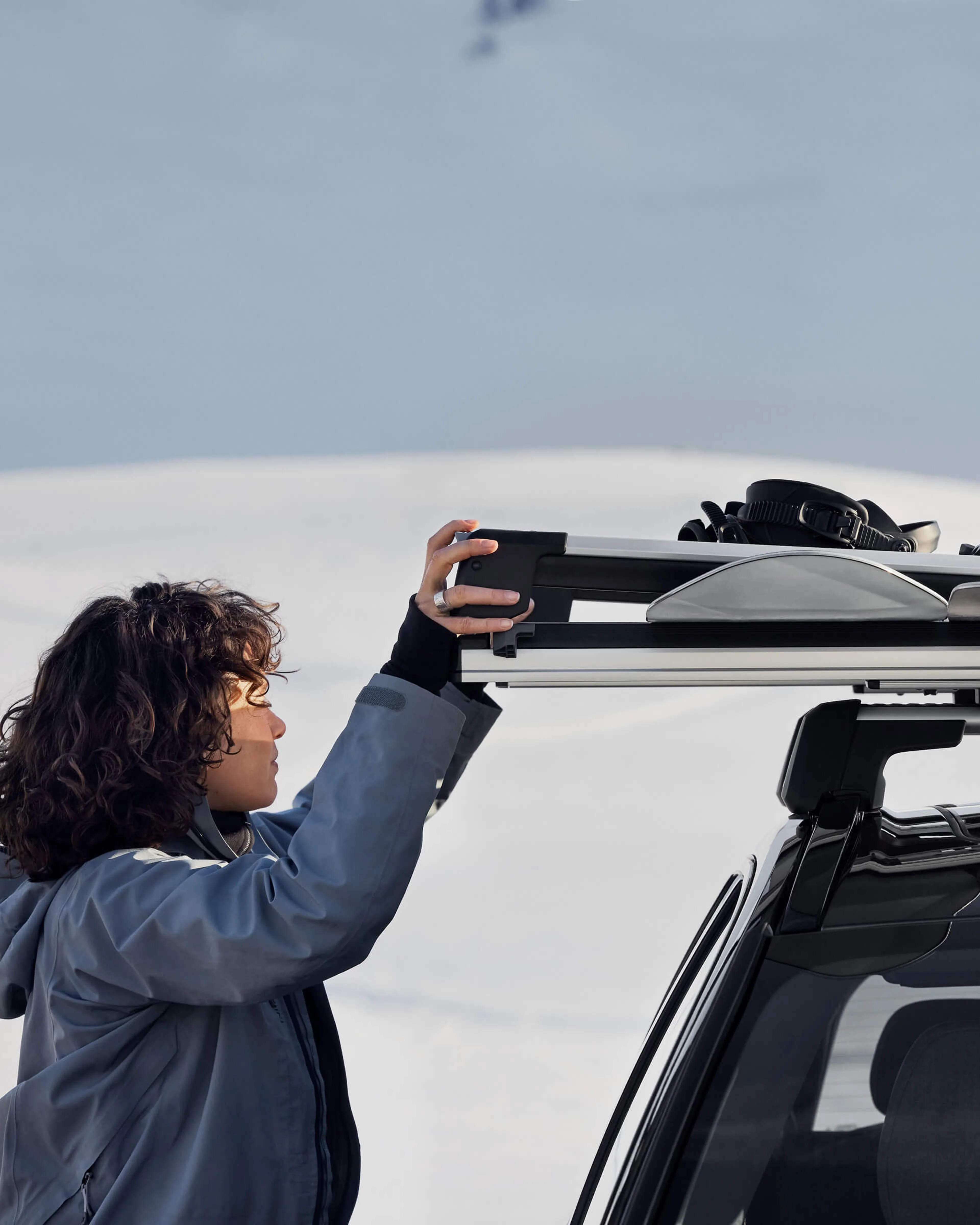 Woman pulling out rack with snowboard and skis