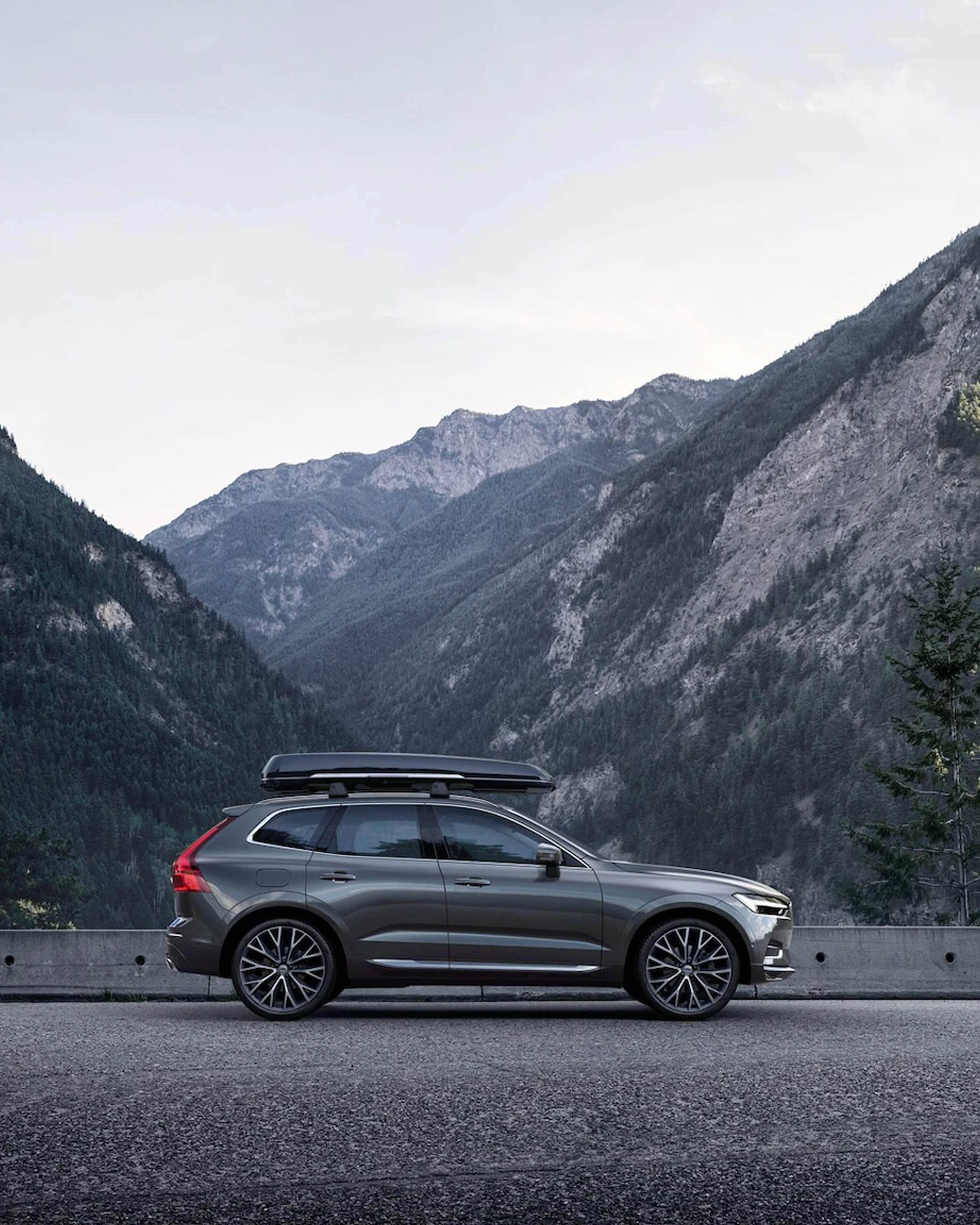 Sidestilt Grønn XC60 på en bro med fjell i bakgrunnen