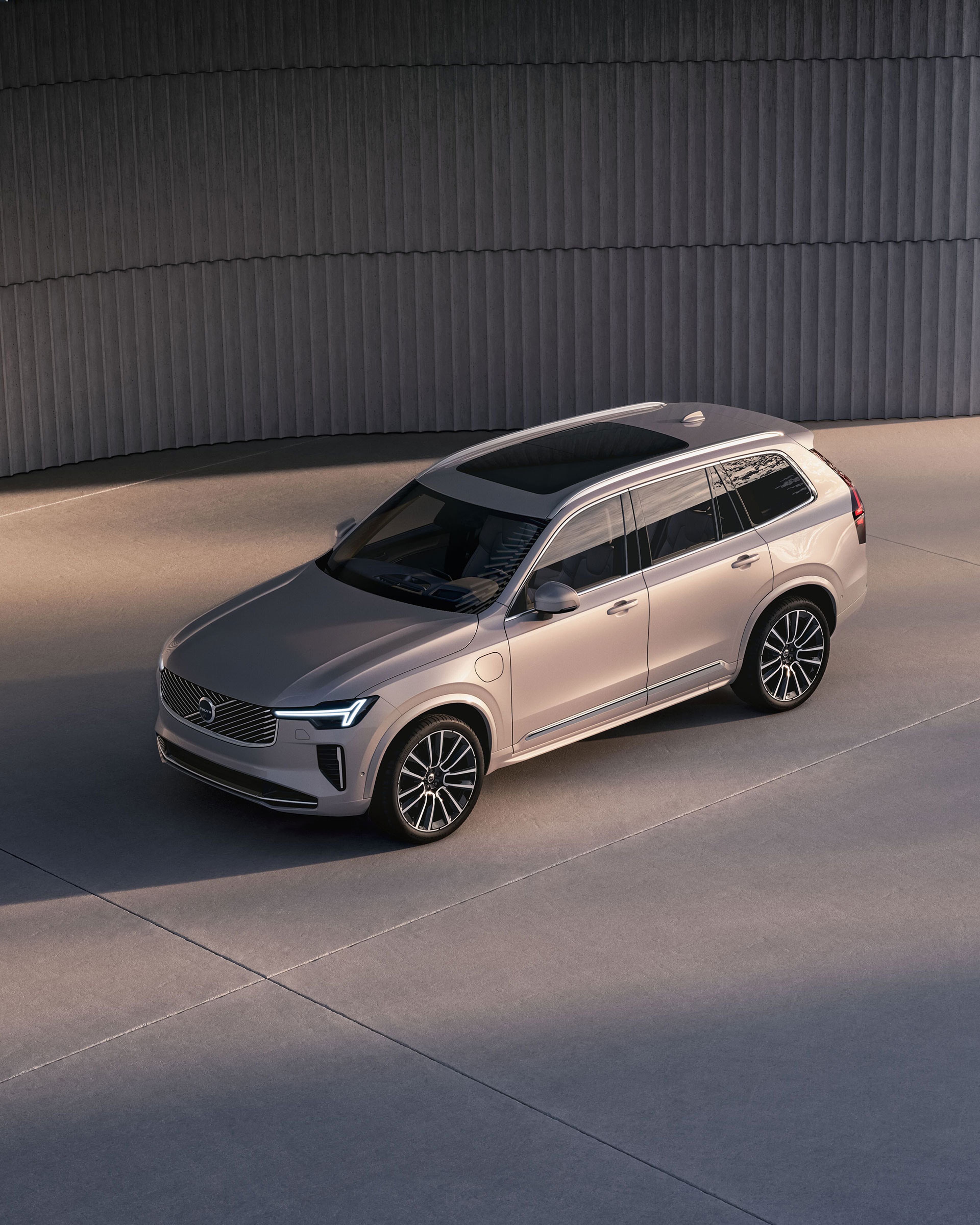 Volvo XC90 beige stationné sur une surface en béton, vu en plongée, avec design moderne et mur incurvé en arrière-plan