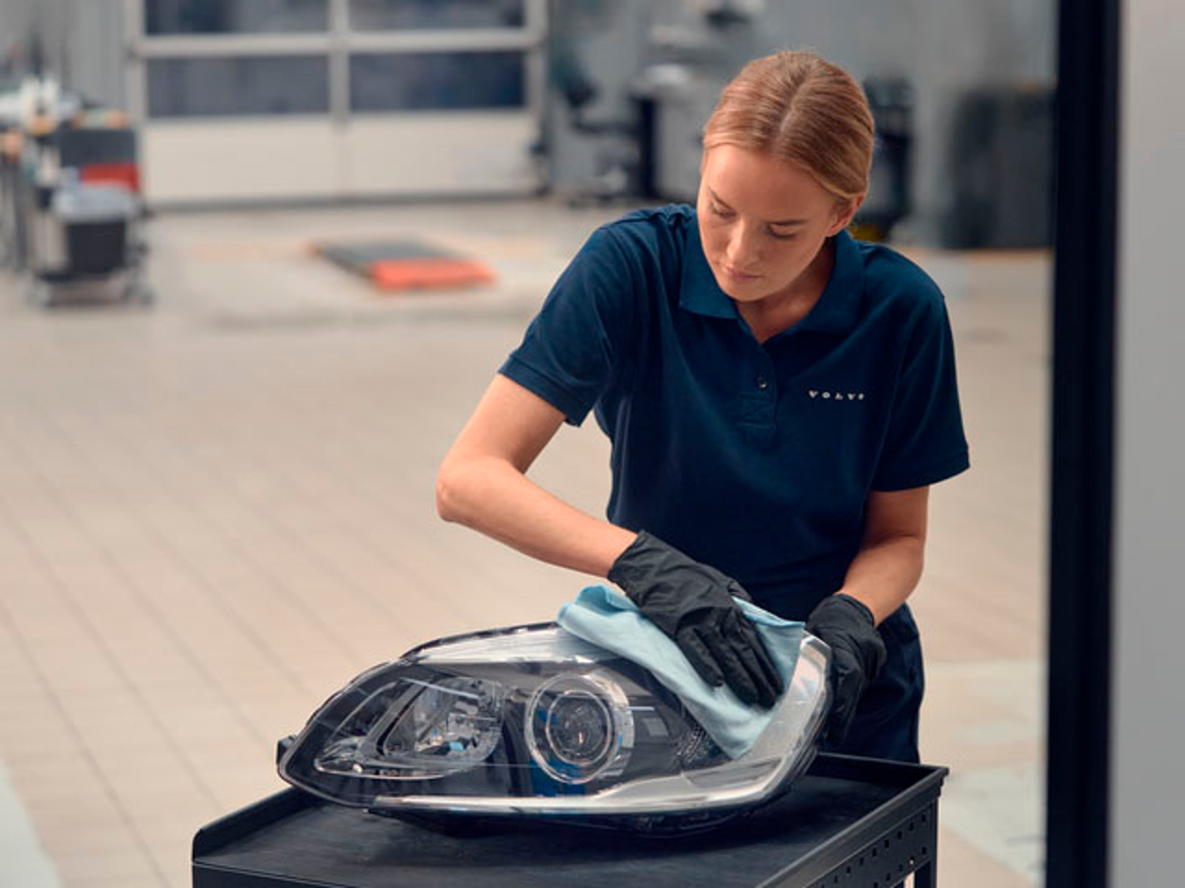 Una chica en un taller manipulando un faro original Volvo