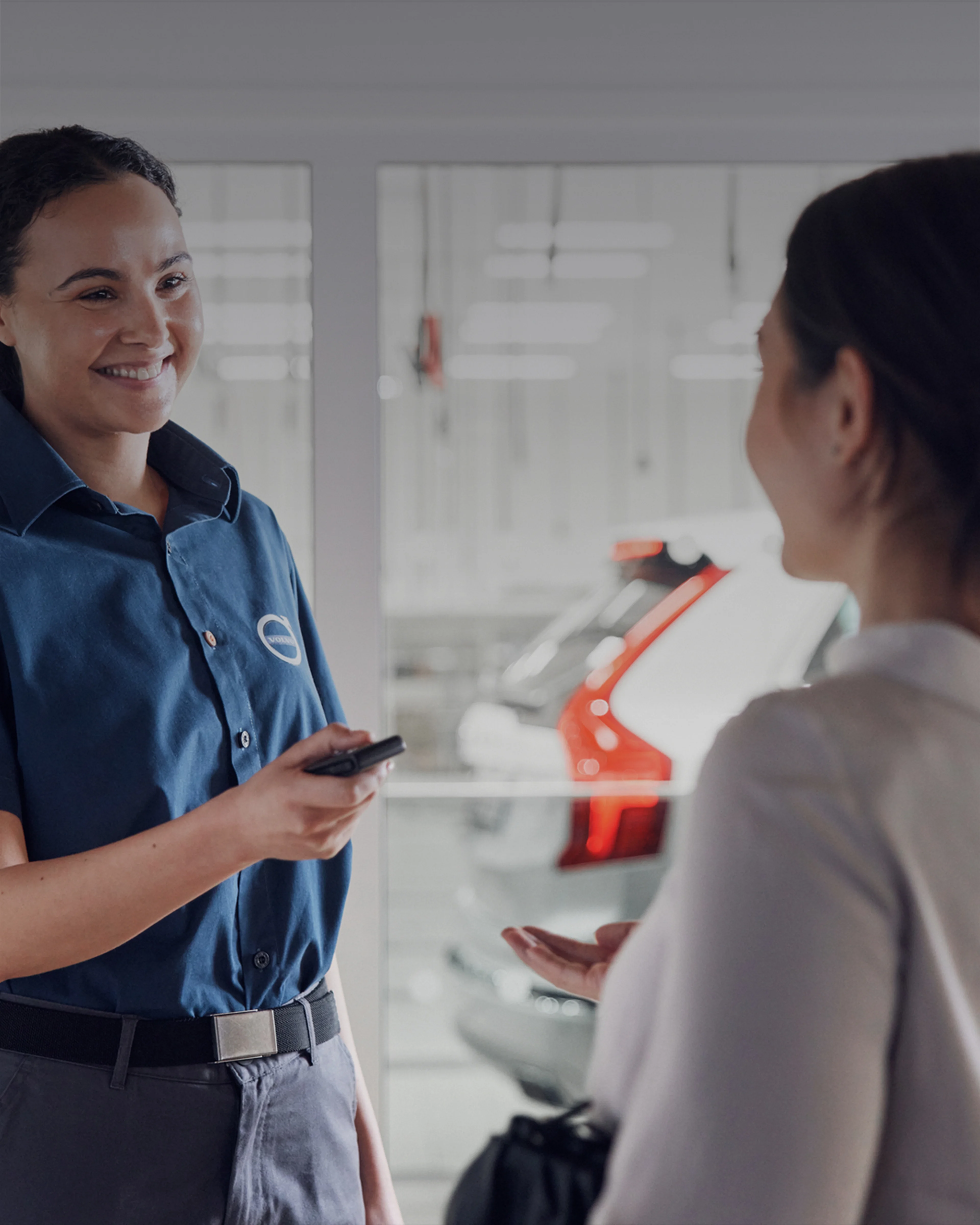 Una mujer técnico de servicio Volvo platicado con otra mujer.