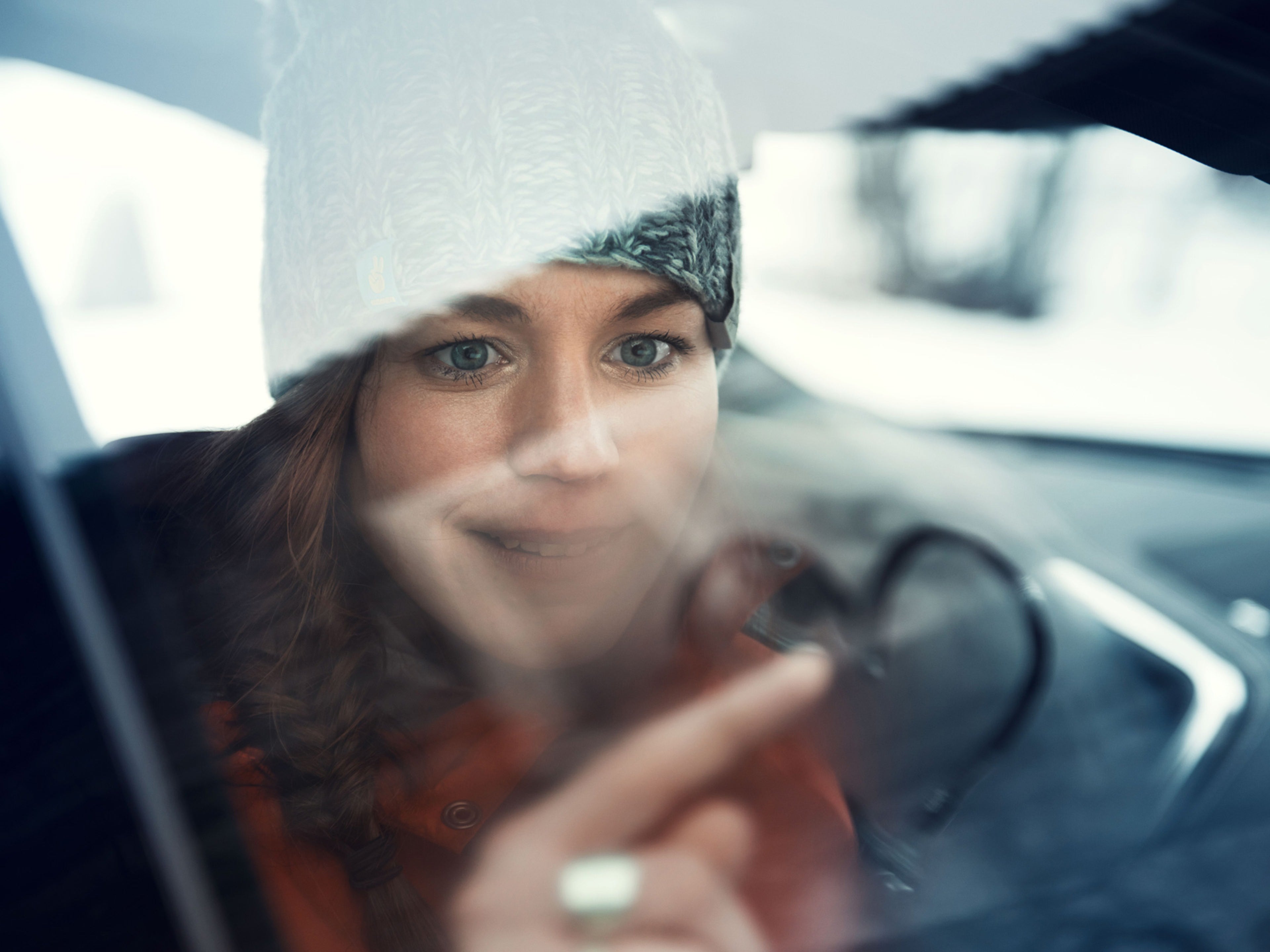 Una mujer dentro de un auto dibujando un corazón en la ventana.