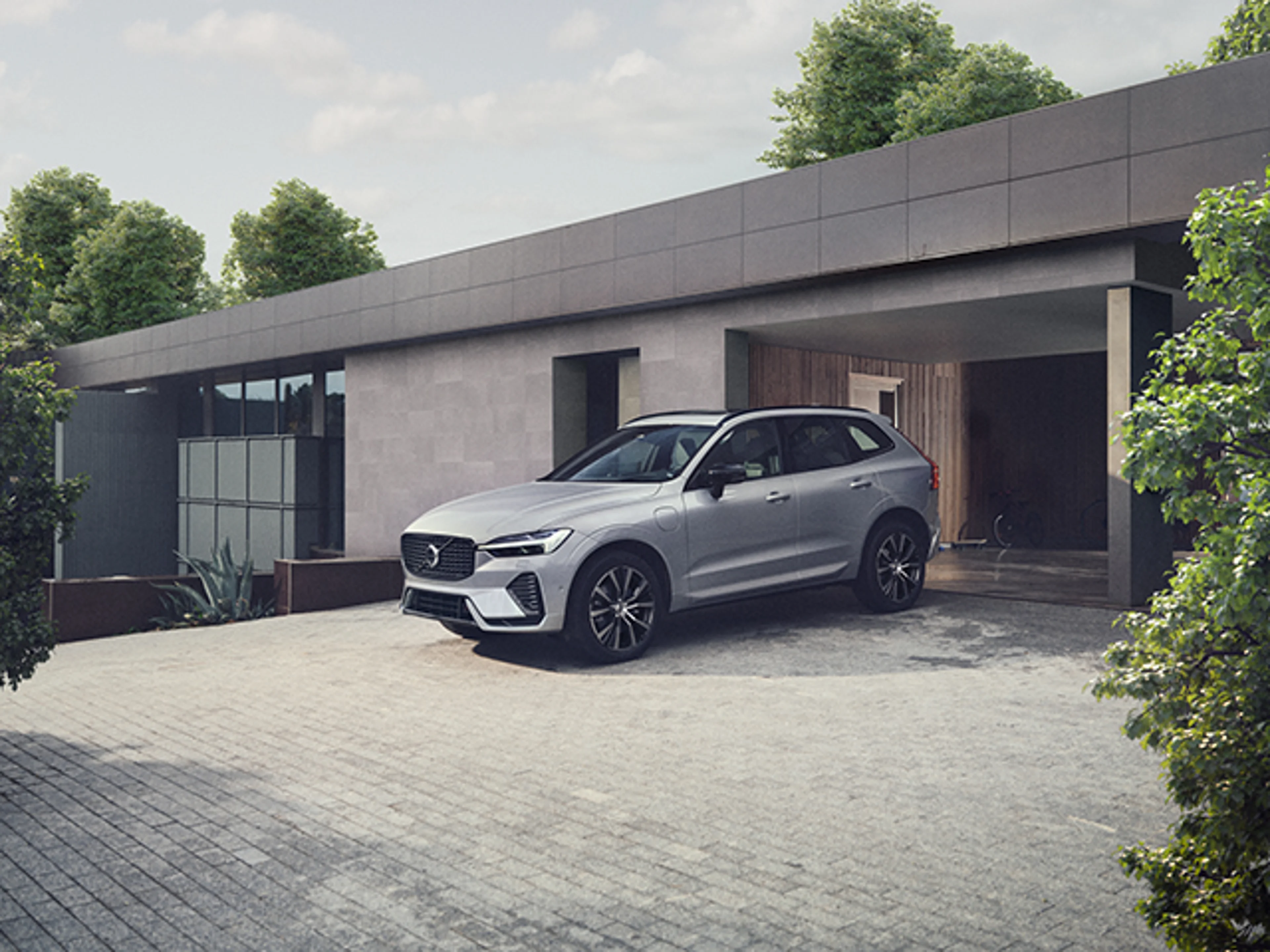 Silvrig Volvo XC60 Recharge parkerad på uppfart